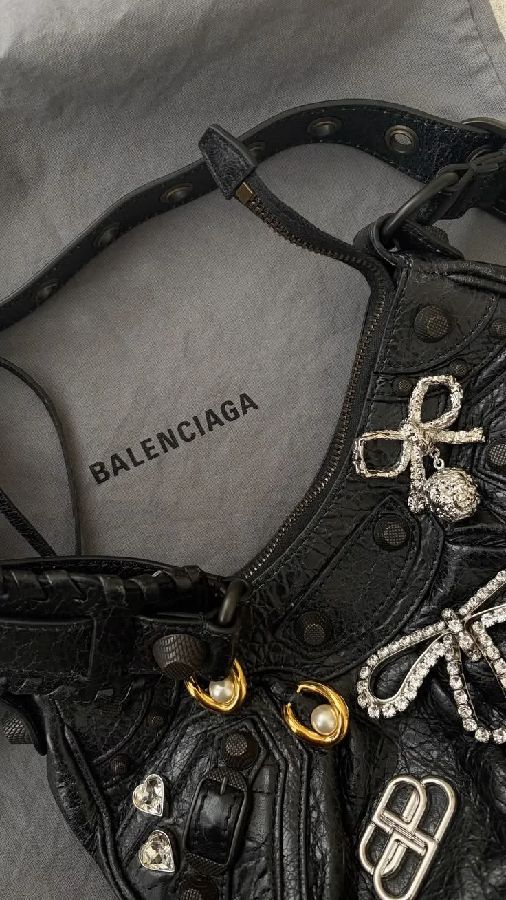 Black handbag with gold and silver jewelry embellishments inside a Balenciaga box.