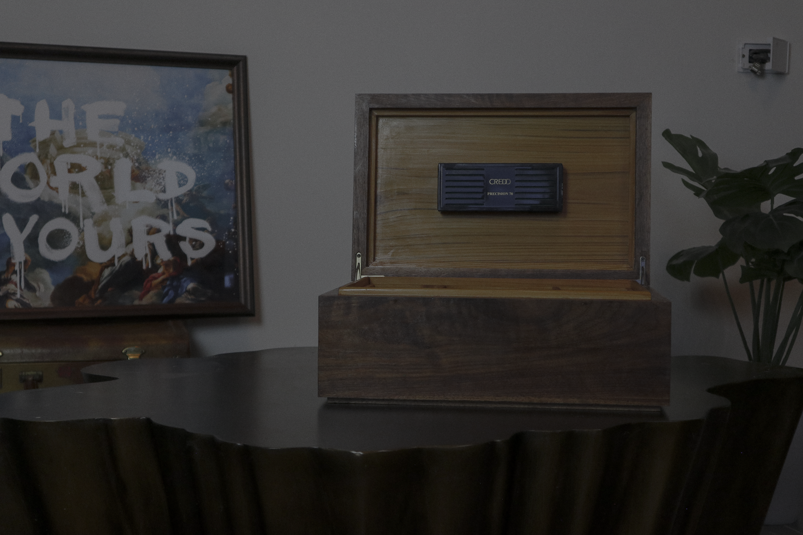 An open cigar humidor with a black Credo Precision 70 hygrometer mounted on the inside lid, sitting on a dark table.