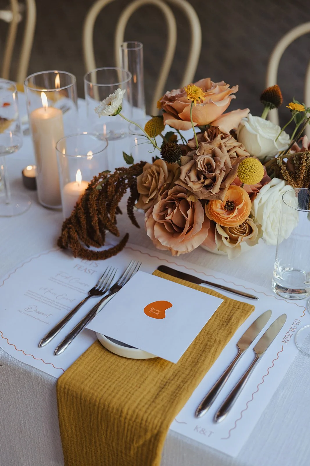 Elegant table setting with a floral centerpiece, lit candles, and place cards for a formal event.