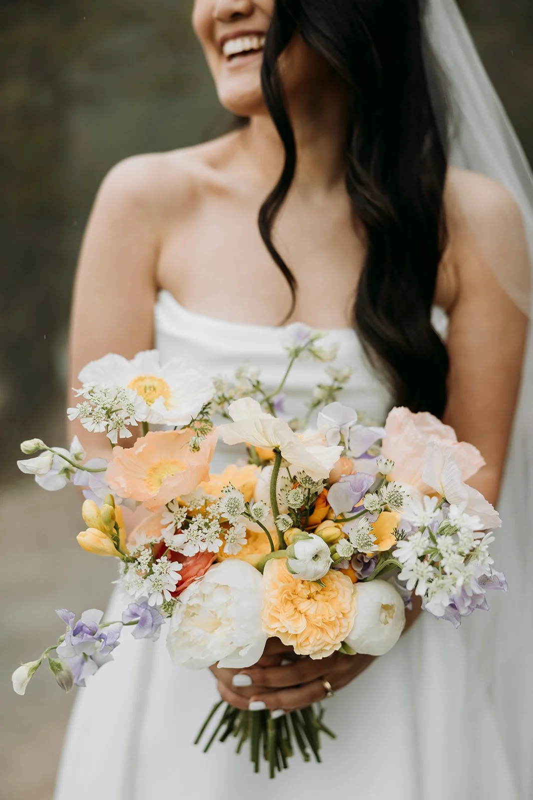 A woman in a wedding dress holding a bouquet of light-colored flowers.