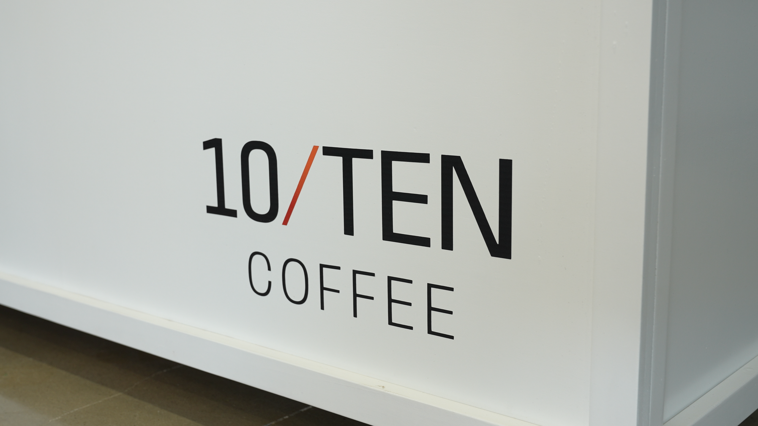 Sign indicating '10/TEN COFFEE' with partial additional text below.