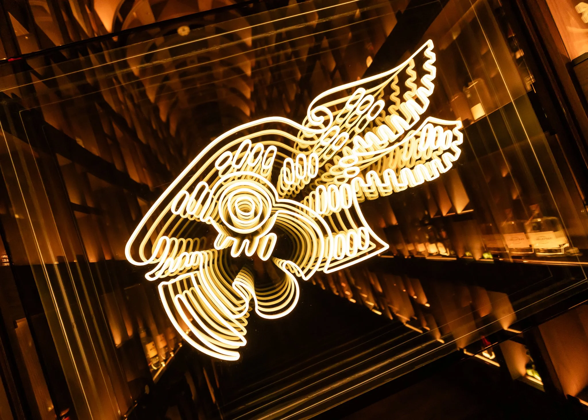 Neon sign display with the words 'Good Vibes' and decorative swirling lines, mounted on a reflective surface with warm lighting effects.