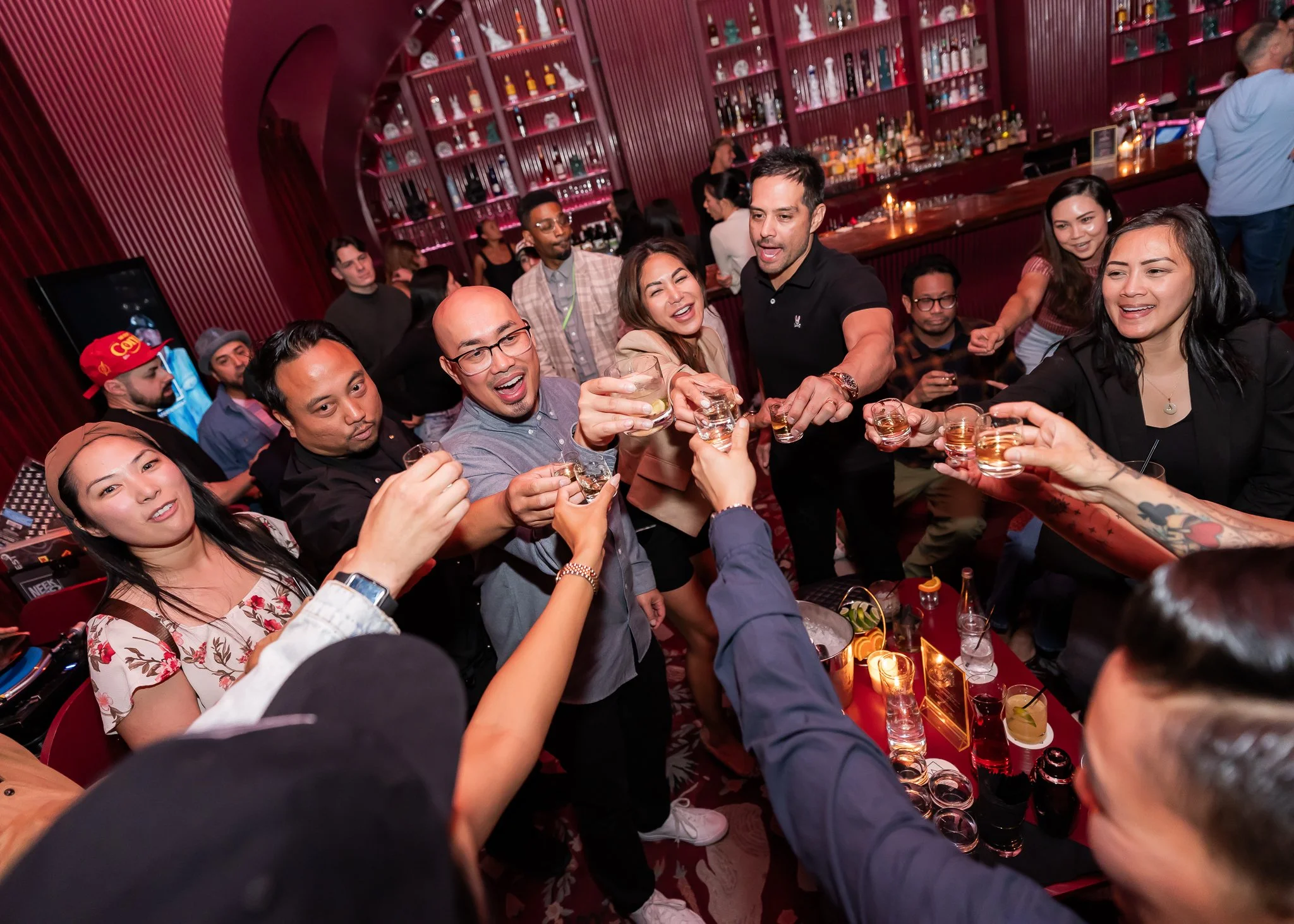 People in a bar raising shot glasses together in celebration.