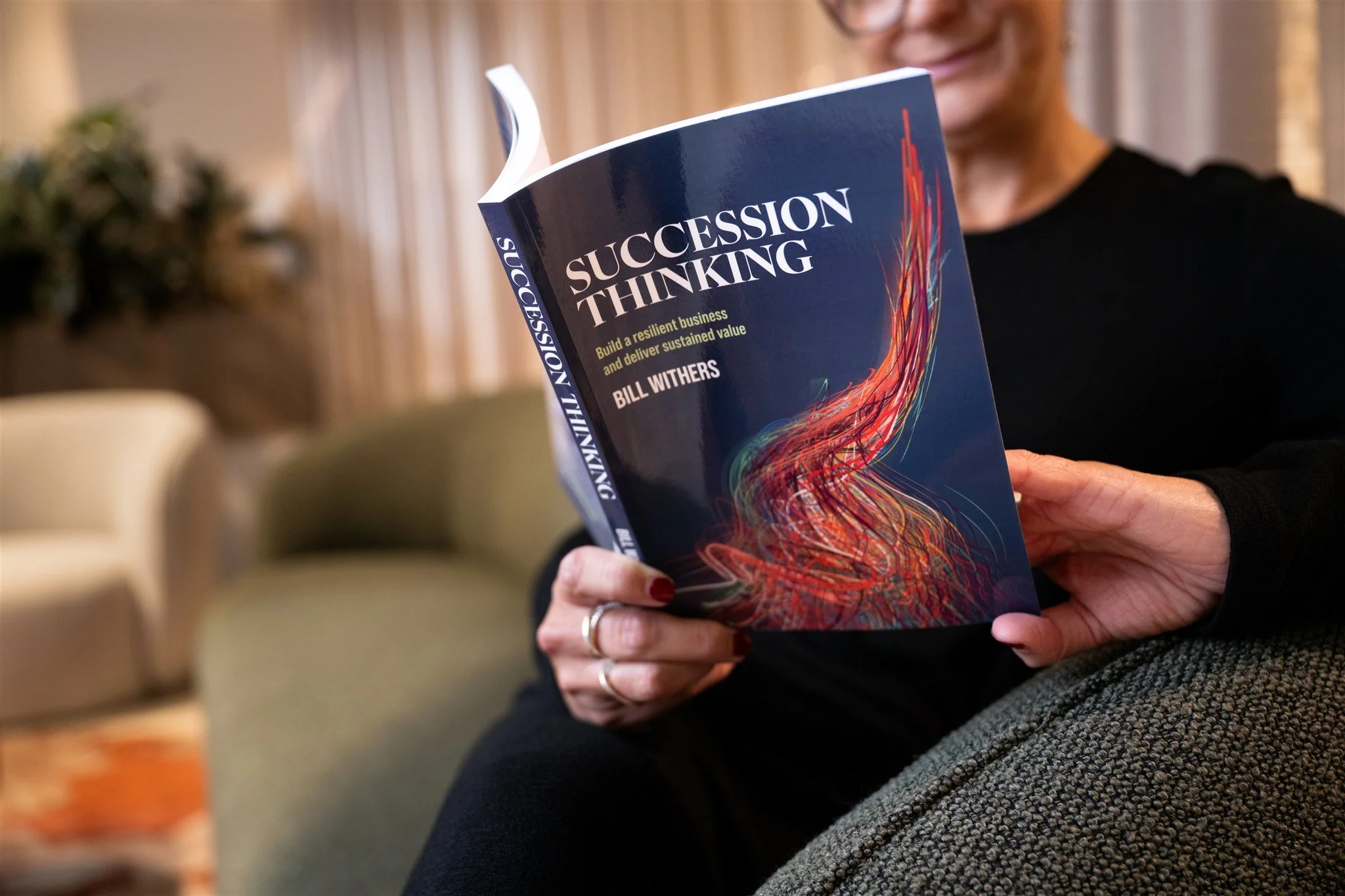 Person holding a book titled 'Succession Thinking' by Bill Withers