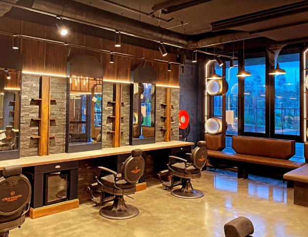 Hair salon with styling stations, chairs, mirrors, and a cozy seating area near large windows.