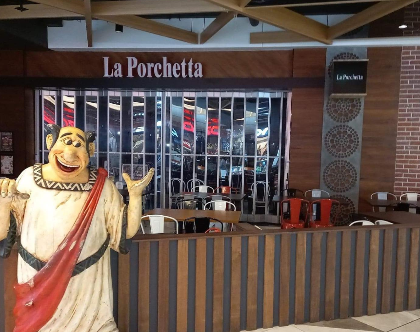 Outside view of La Porchetta restaurant with a smiling clown statue in front.