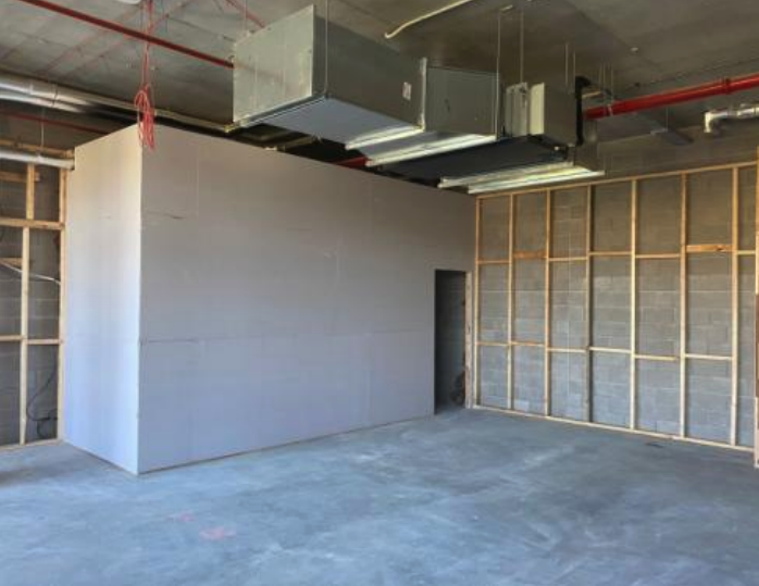 Construction site with drywall and wall framing, exposed concrete floor, and HVAC ductwork on ceiling.