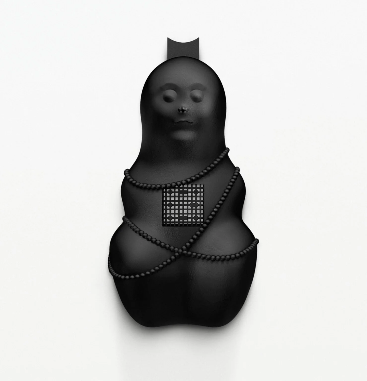 Black sculpture with abstract human face, adorned with bead necklaces and a geometric square on its chest, against a white background.