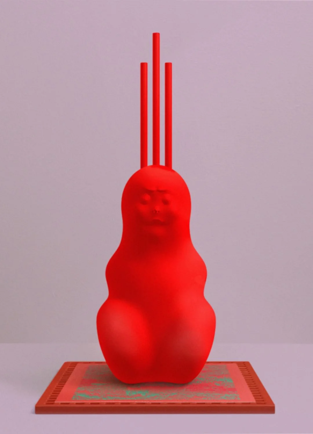 A red plastic sculpture of a human face with closed eyes and lips, attached to a curvy, abstract form, with three red rods extending upward from the top, placed on a textured base.