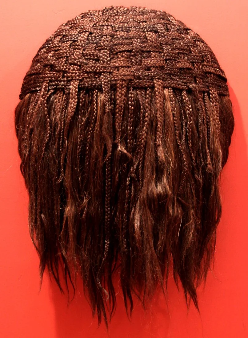 Wig with braided and loose hair against a red background.