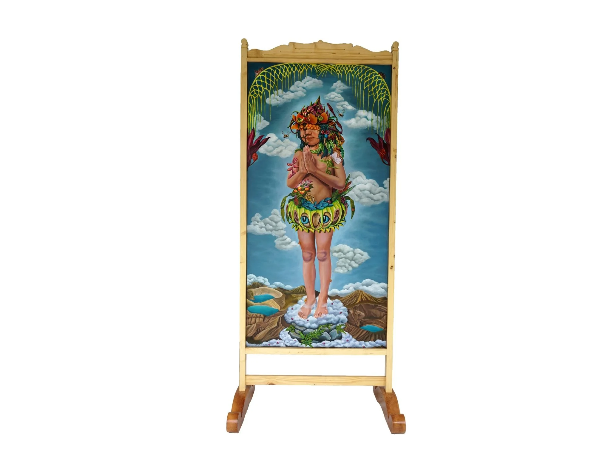 A colorful spiritual artwork on a wooden standing panel depicts a person with hands in prayer, surrounded by clouds, mountains, and nature elements, with intricate foliar and butterfly details.