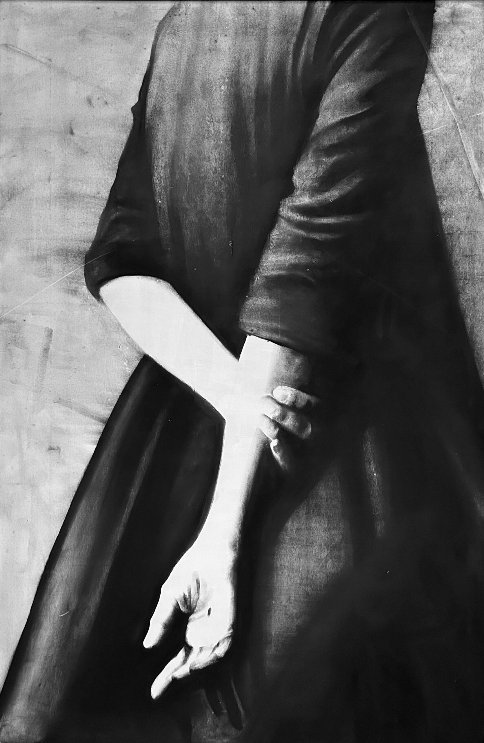 Black and white image of a person holding a large hammer with one hand, wearing a leather jacket and shorts, standing on a wooden floor.