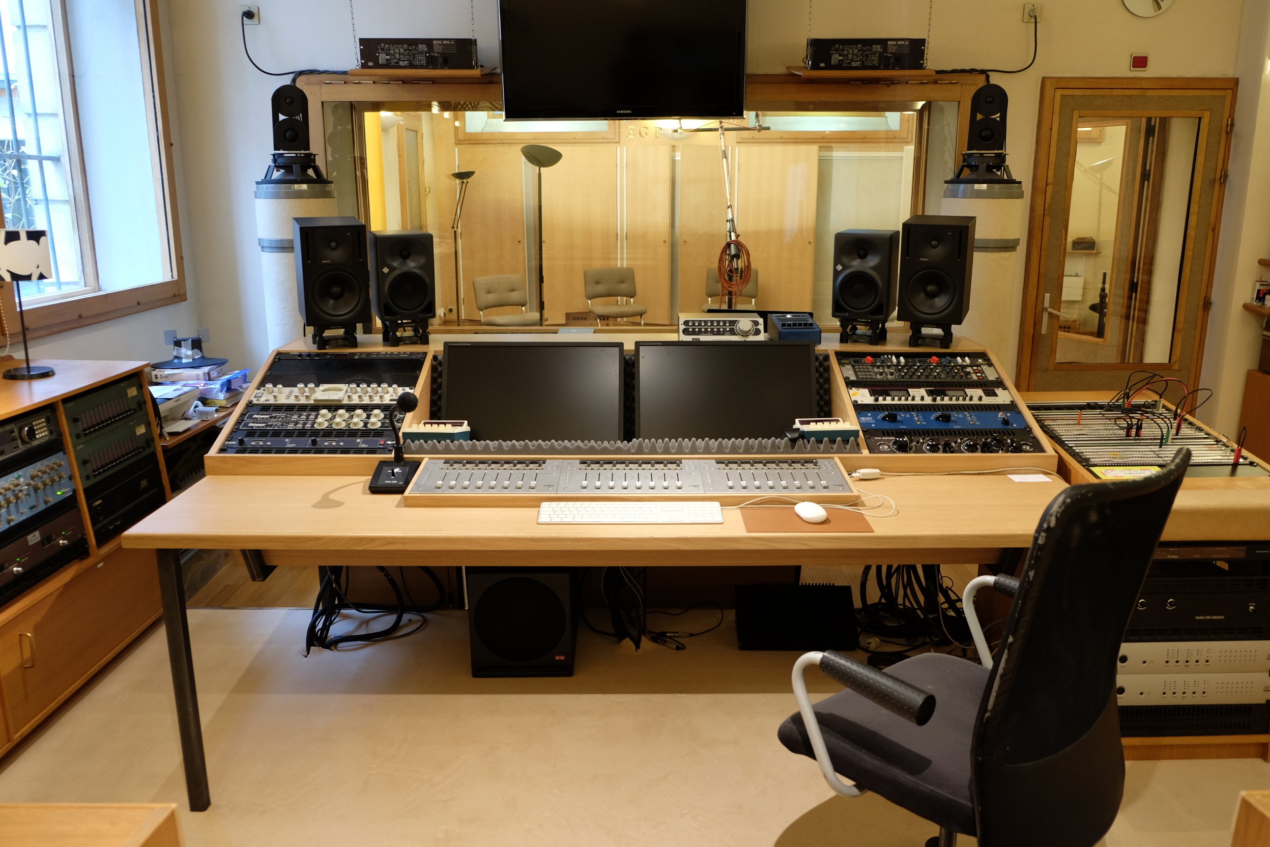 Une cabine de studio d'enregistrement avec des équipements audio et deux écrans