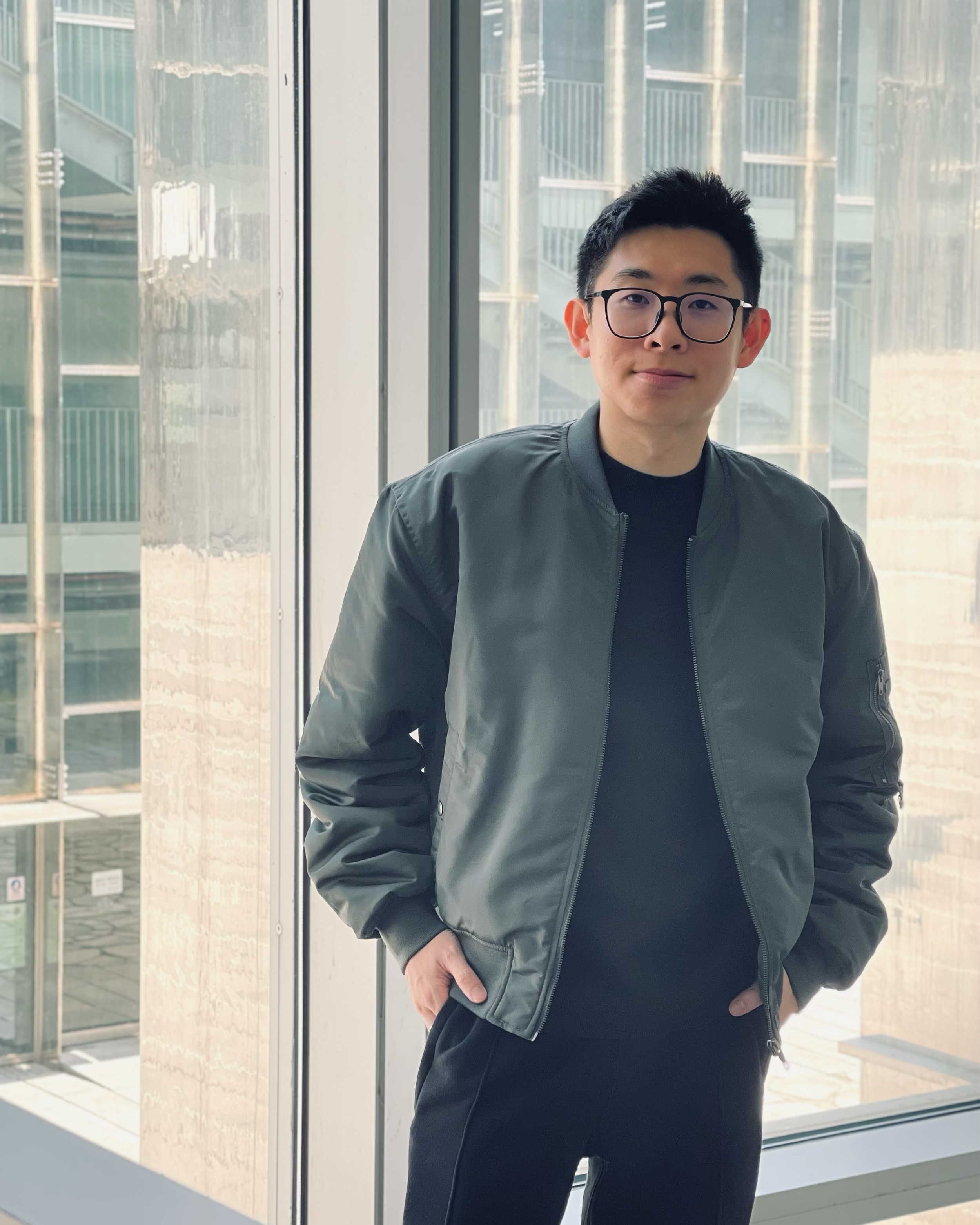 Portrait of Ar. Koh Kah Tzun, co-founder of KOY_LAB /ARCHITECTS, standing against a glass architectural backdrop. Melbourne-trained architect specialized in data centers and Australian residential growth.