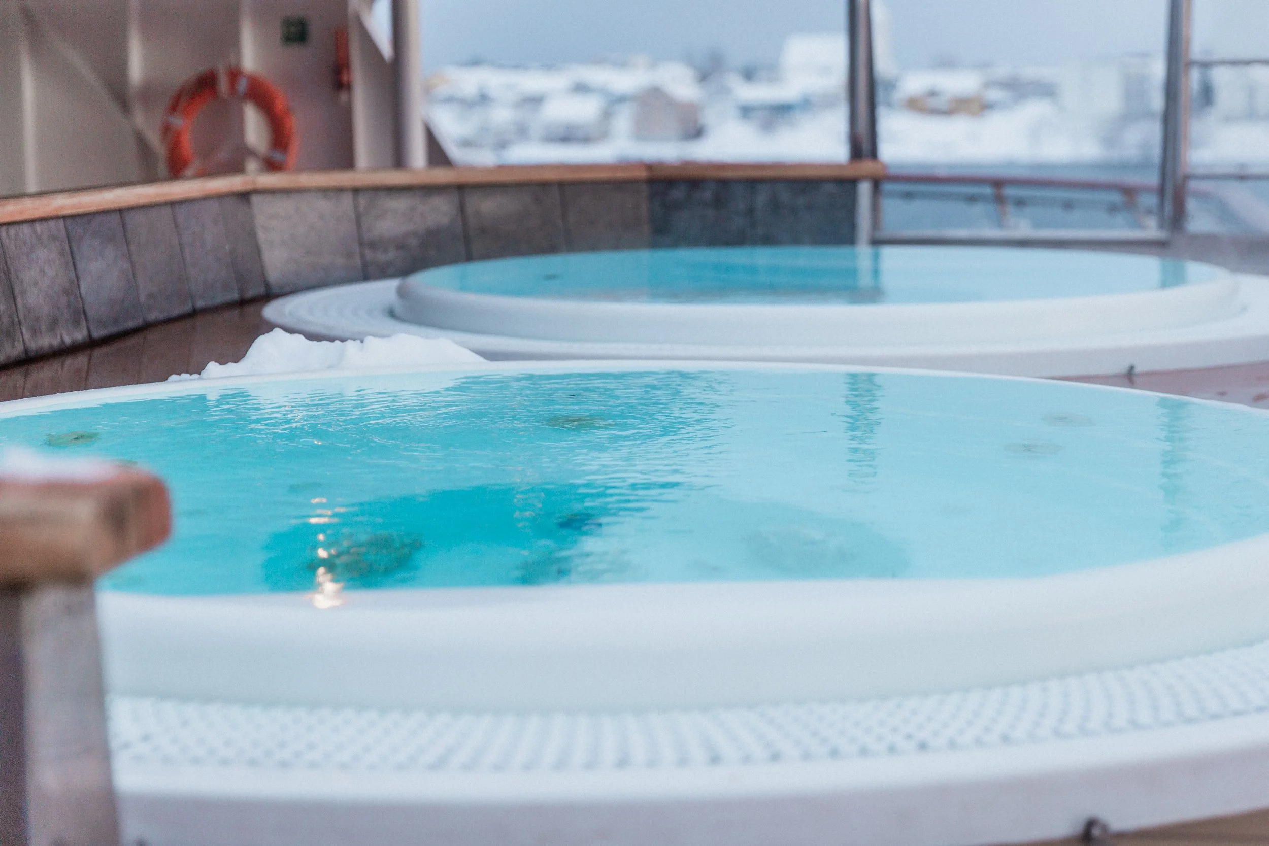 Two outdoor hot tubs on MS Spitsbergen, filled with warm water and surrounded by snowy Arctic scenery.