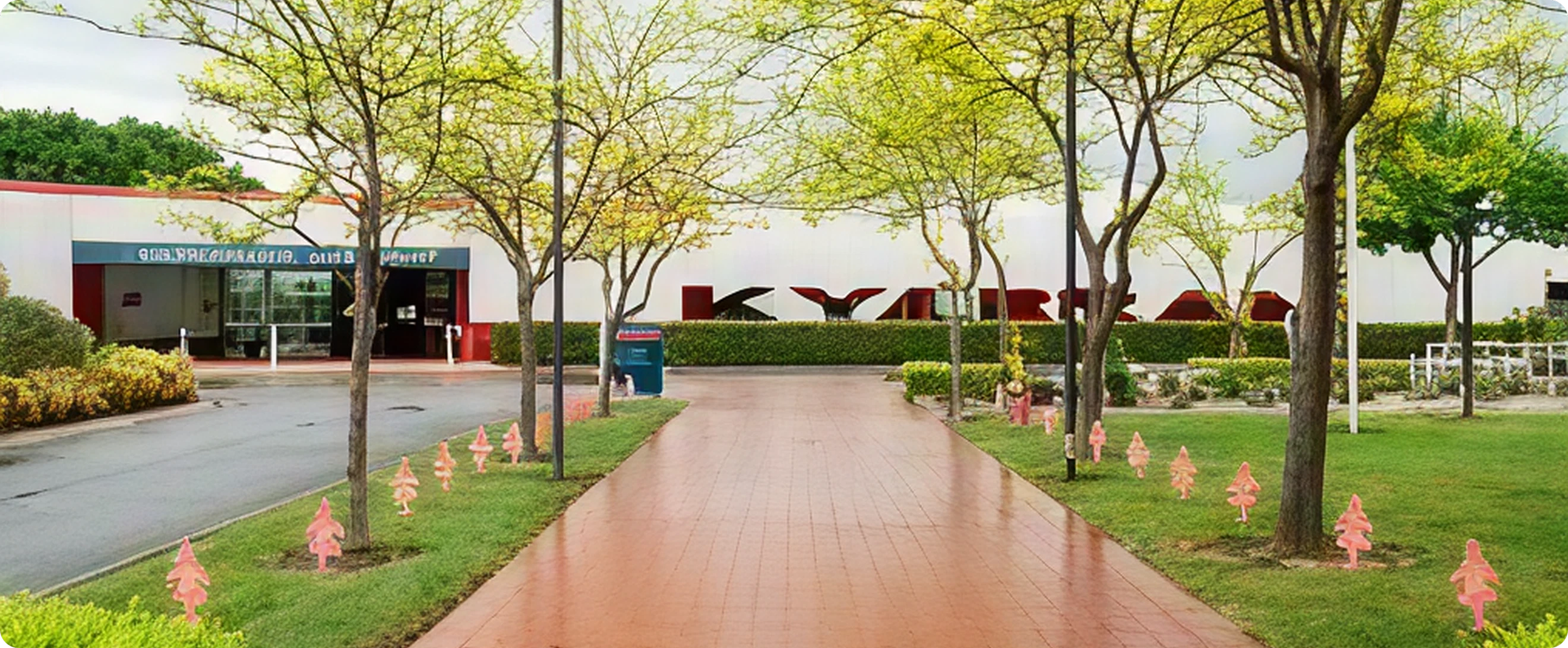 Sidewalk leading to a building entrance with trees and small pink and orange decorations along the grass.