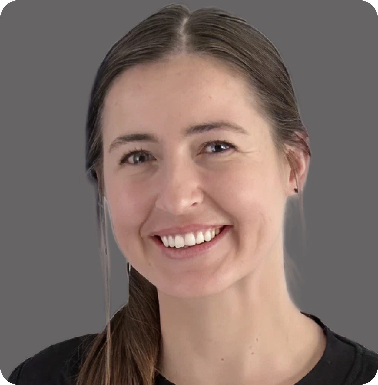 Close-up of a smiling young woman with brown hair, blue eyes, and a black top against a gray background.