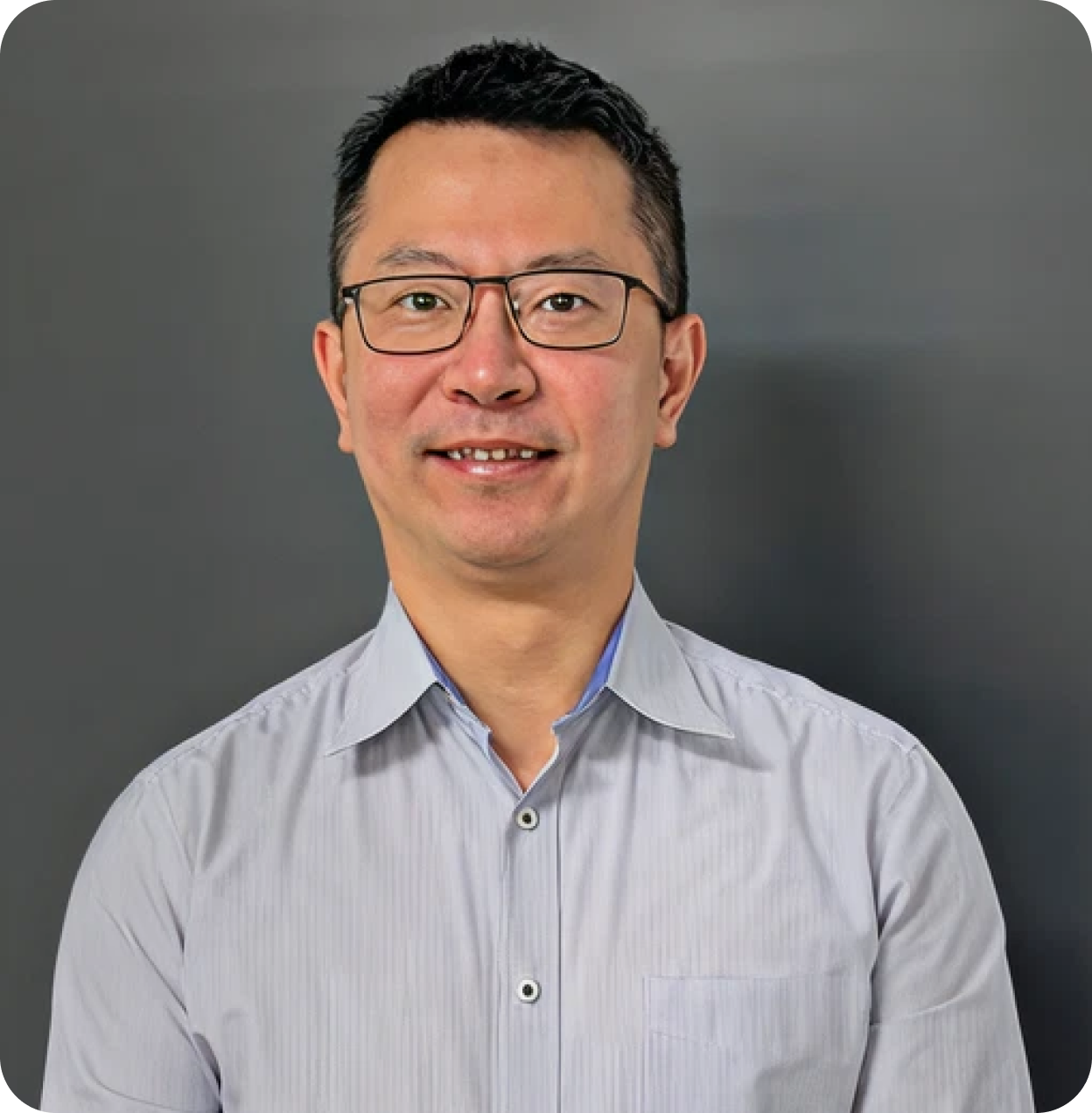Headshot of a smiling Asian man wearing glasses and a light gray button-up shirt against a dark gray background.