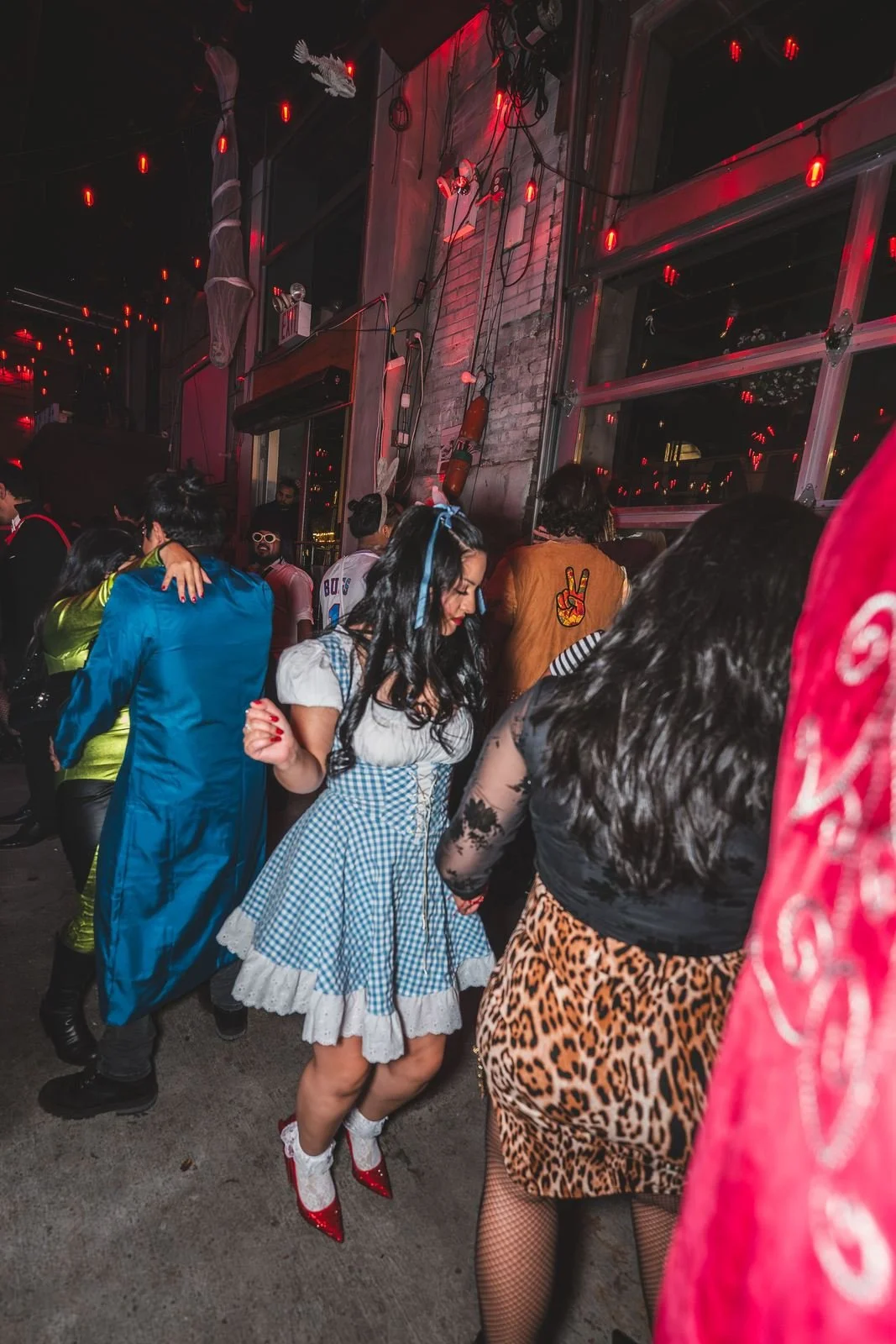 Guests dancing in costumes, including a blue gingham Dorothy dress, at Monstera Nightlife at Sea Wolf in Bushwick, Brooklyn, Halloween 2025