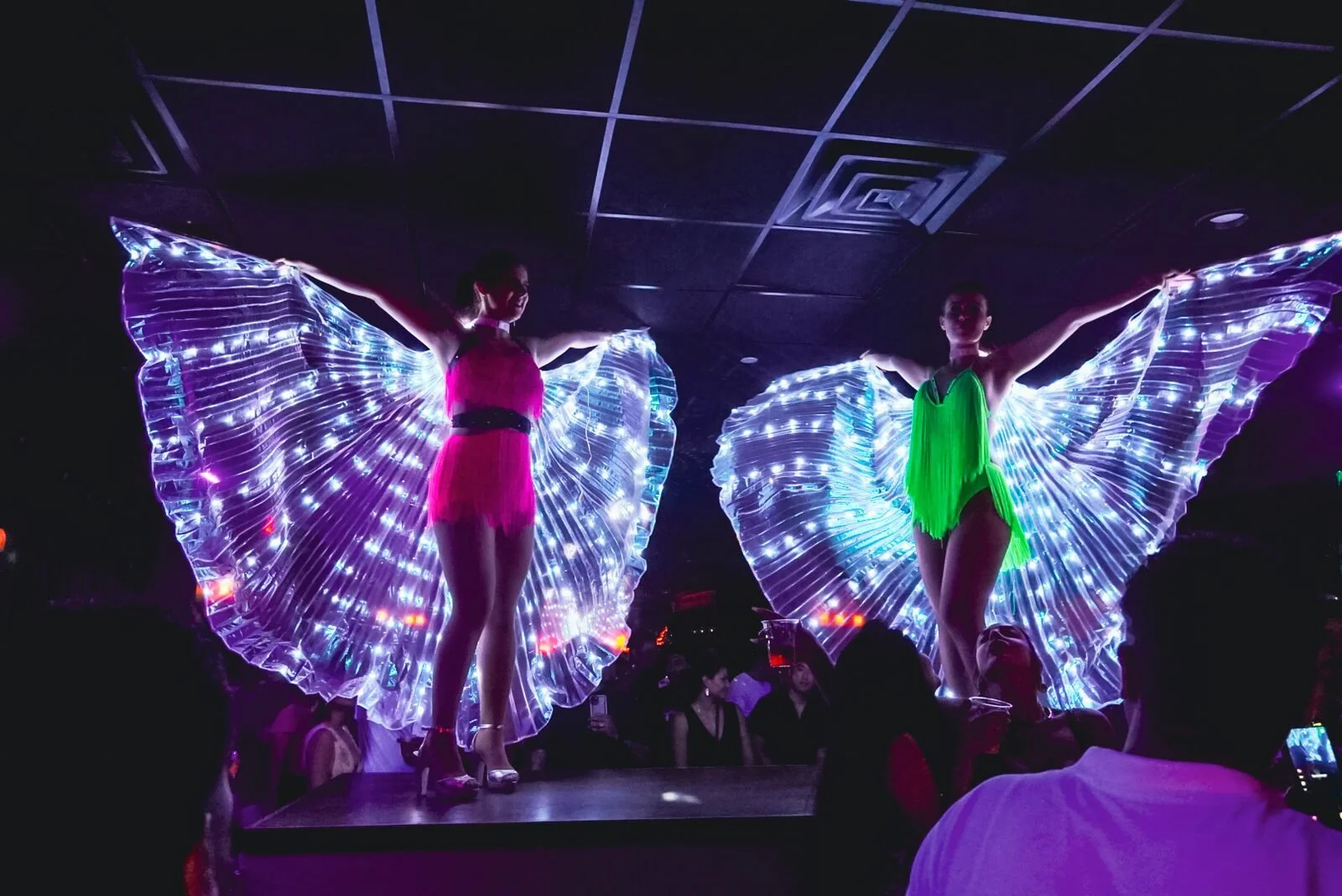 Throwback: two dancers in light-up LED wings on stage at Republic in Williamsburg, Brooklyn