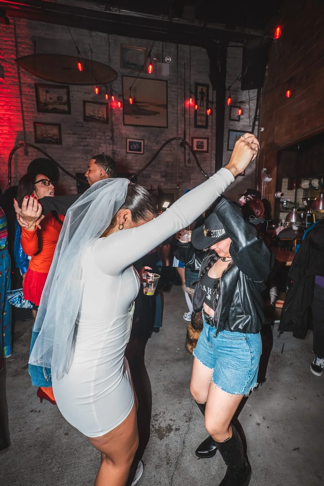 Guest in a white dress and bridal veil dancing with one arm raised at Sea Wolf in Bushwick, Brooklyn