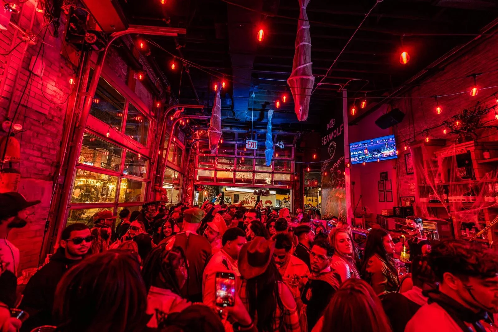Crowd in costumes filling Sea Wolf under red string lights at Monstera Nightlife in Bushwick, Brooklyn, Halloween 2025