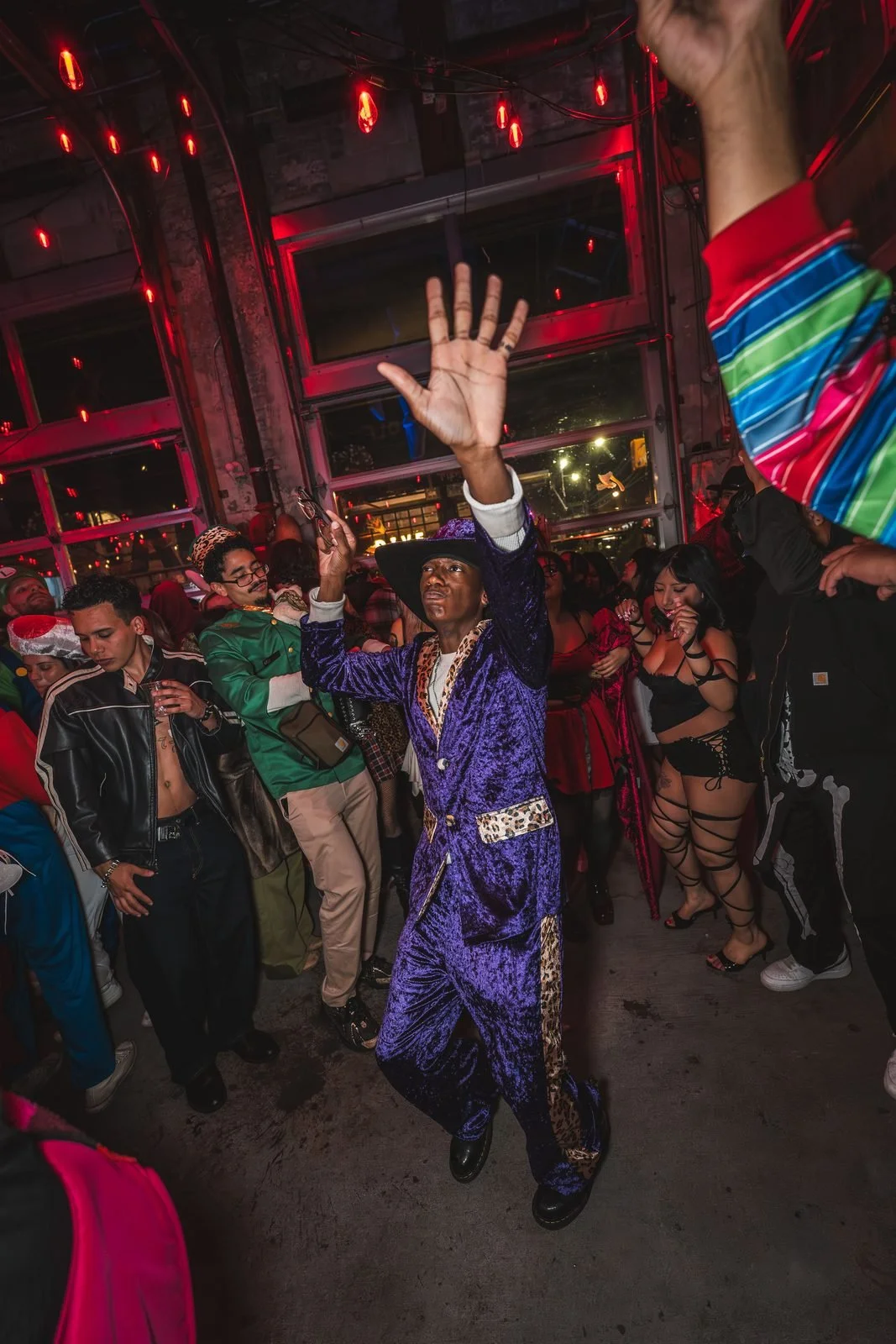 Guest in a purple velvet suit and hat dancing with one arm raised at Monstera Nightlife at Sea Wolf in Bushwick, Brooklyn, Halloween 2025