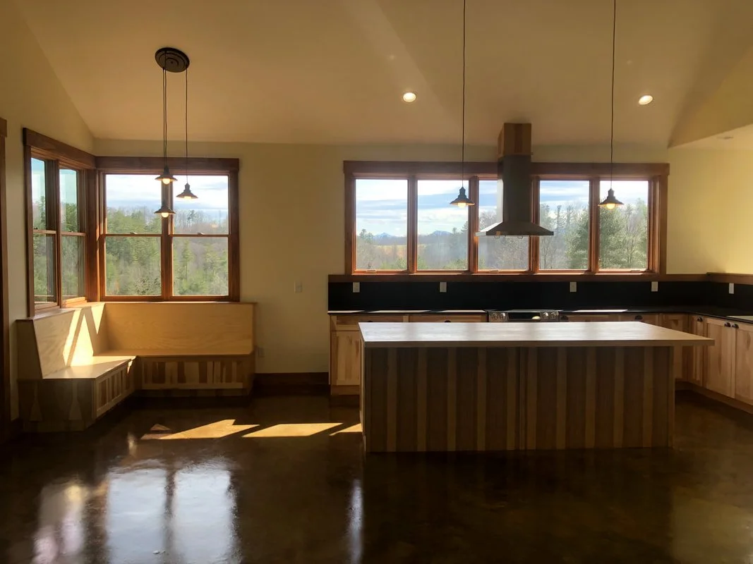 Custom kitchen with wood island, built-in bench seating, and large windows