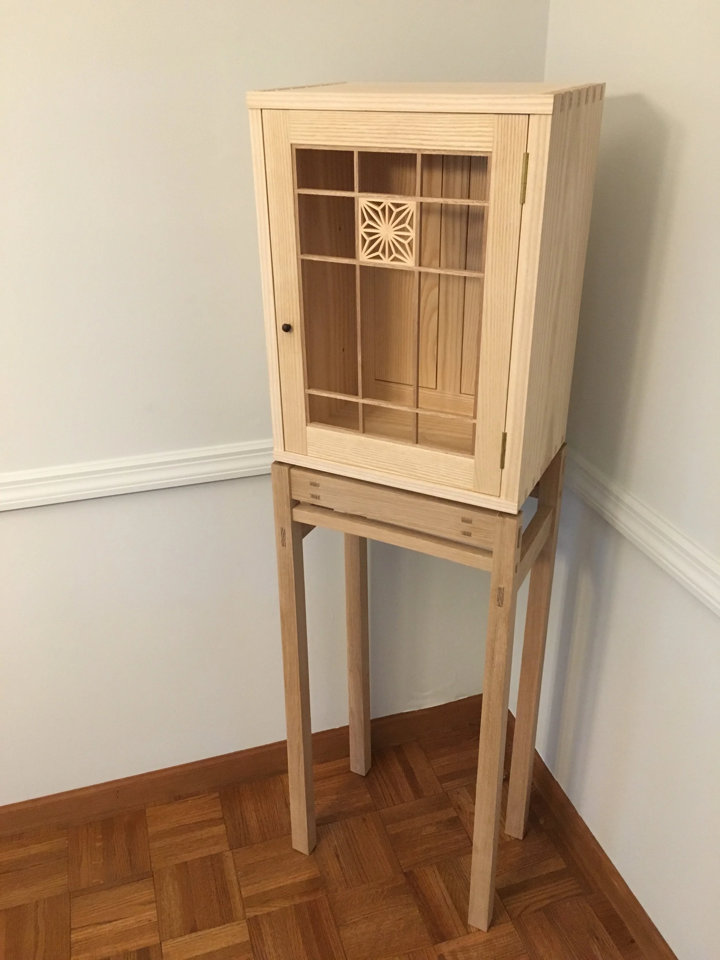 Custom kumiko display case with geometric wood pattern and oak stand