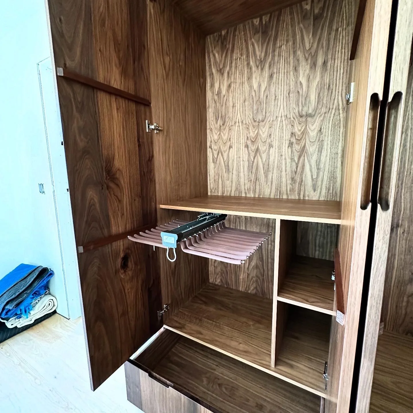 Interior detail of walnut wardrobe with shelves and hanging rail