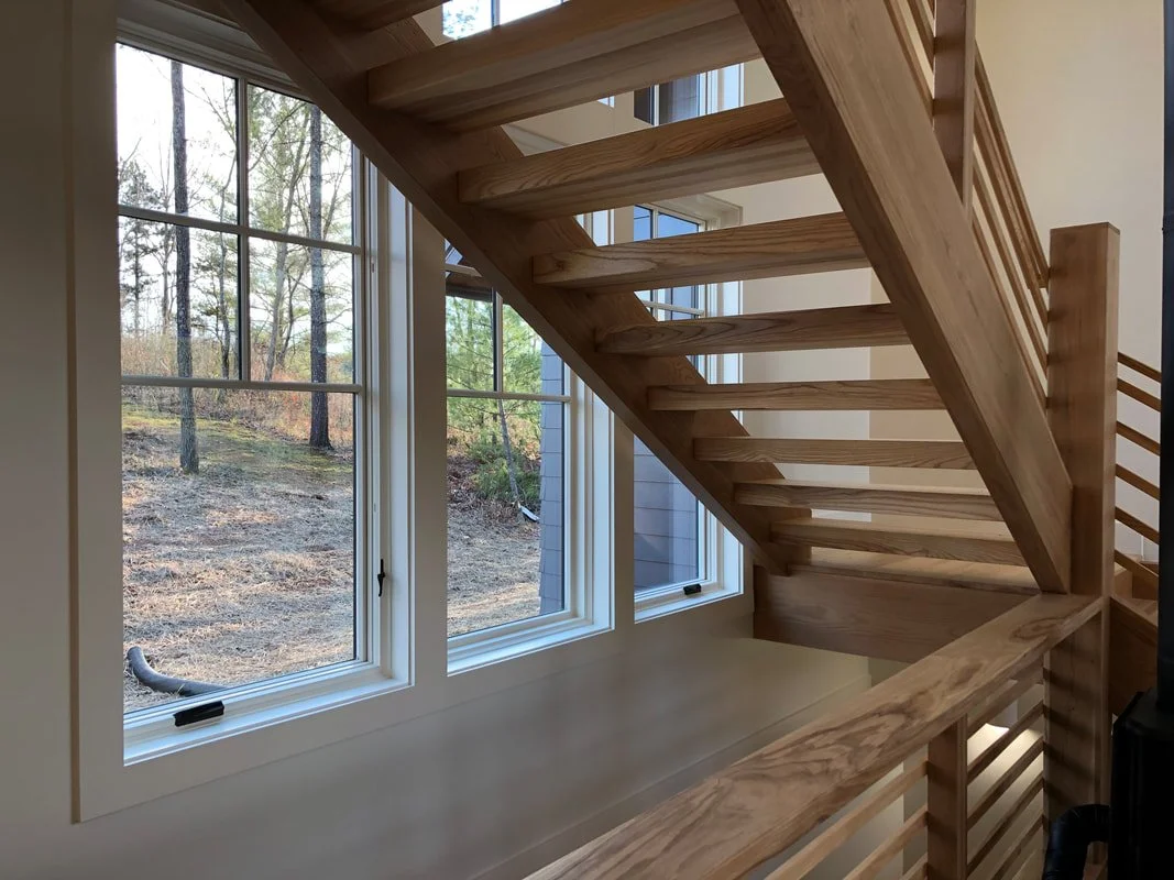 Floating staircase detail with white oak structure and natural light from large windows