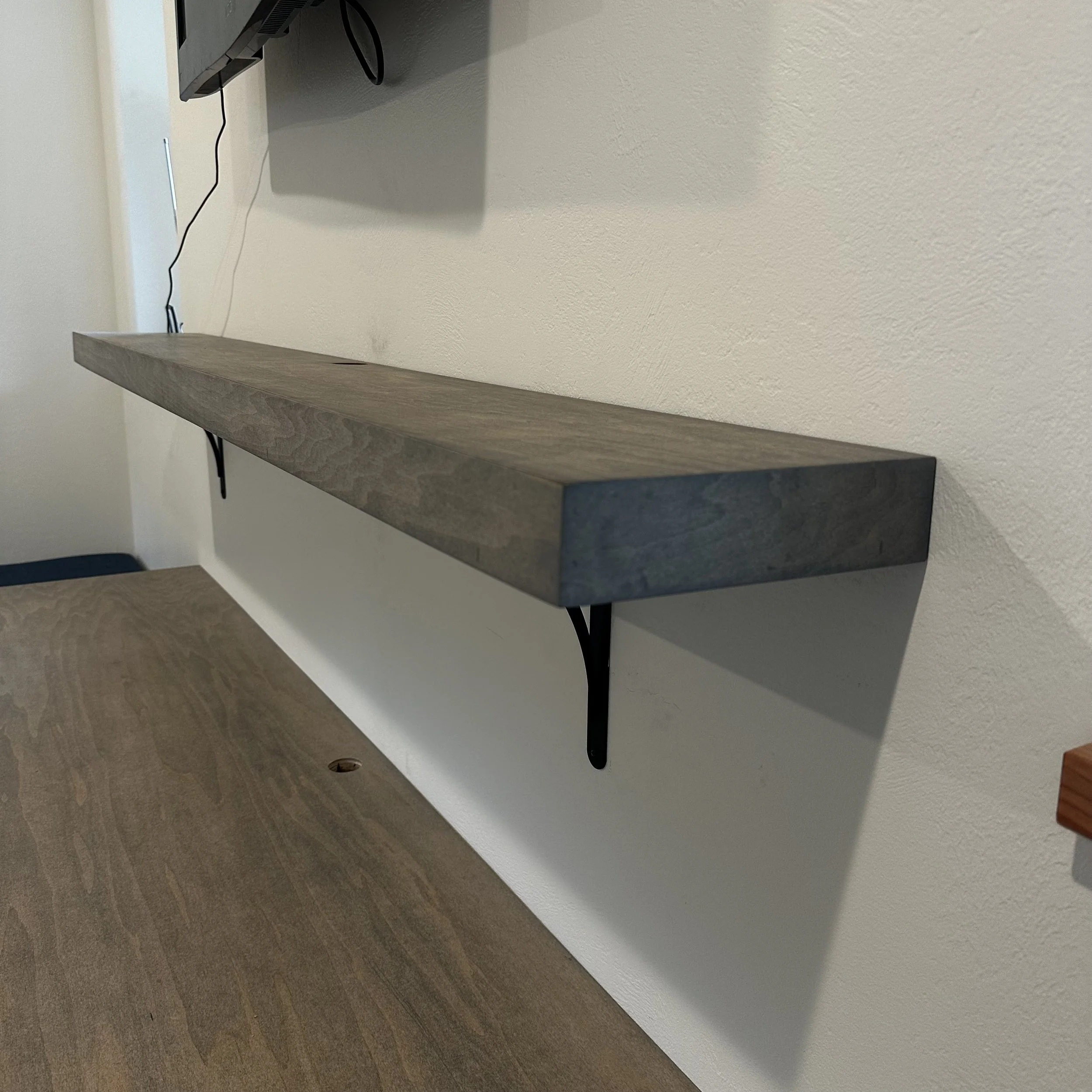 Wall-mounted floating shelf in stained wood with metal bracket support