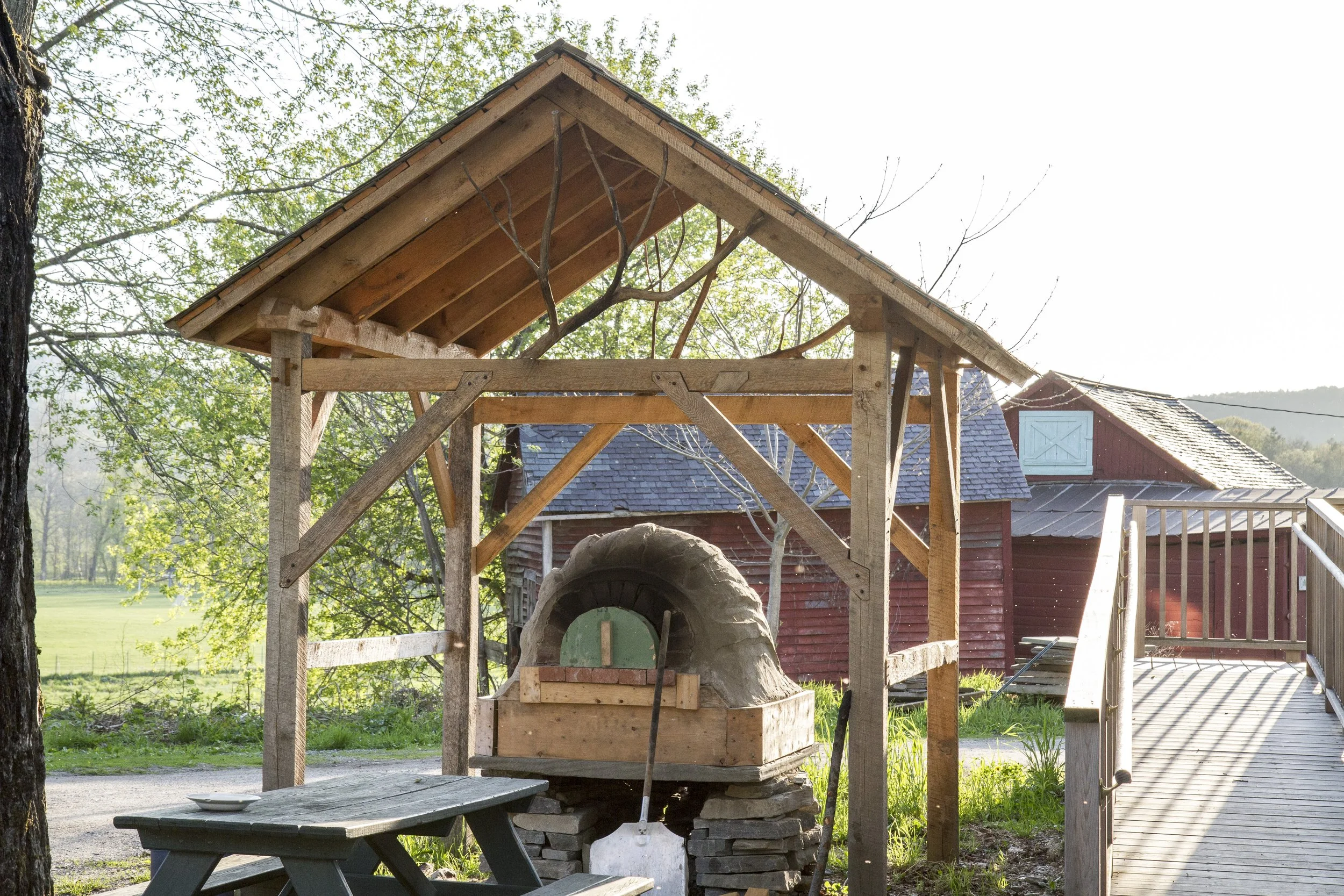 Outdoor timber frame structure with wood-fired cob oven and natural materials