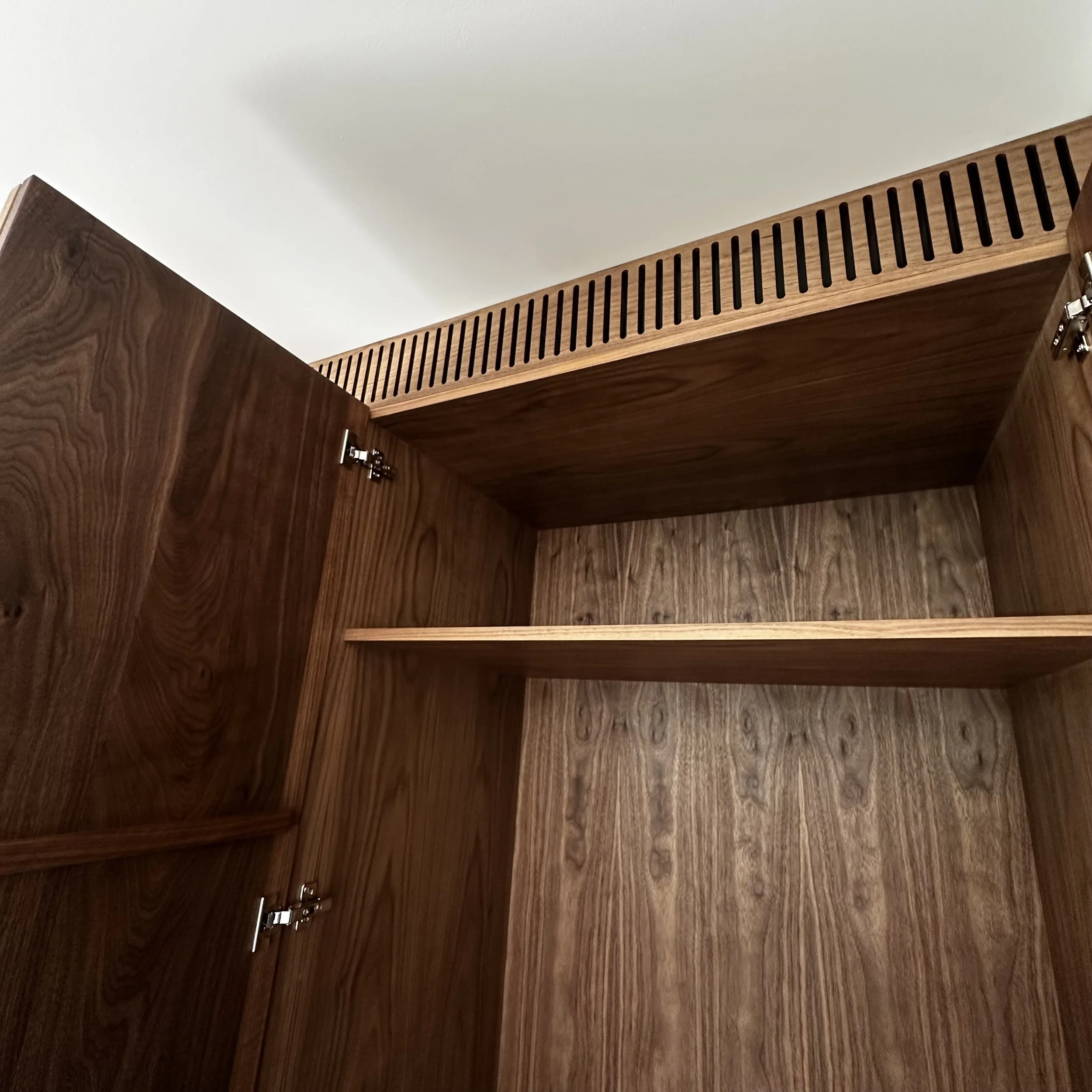 Interior shelving detail in custom walnut wardrobe with natural finish