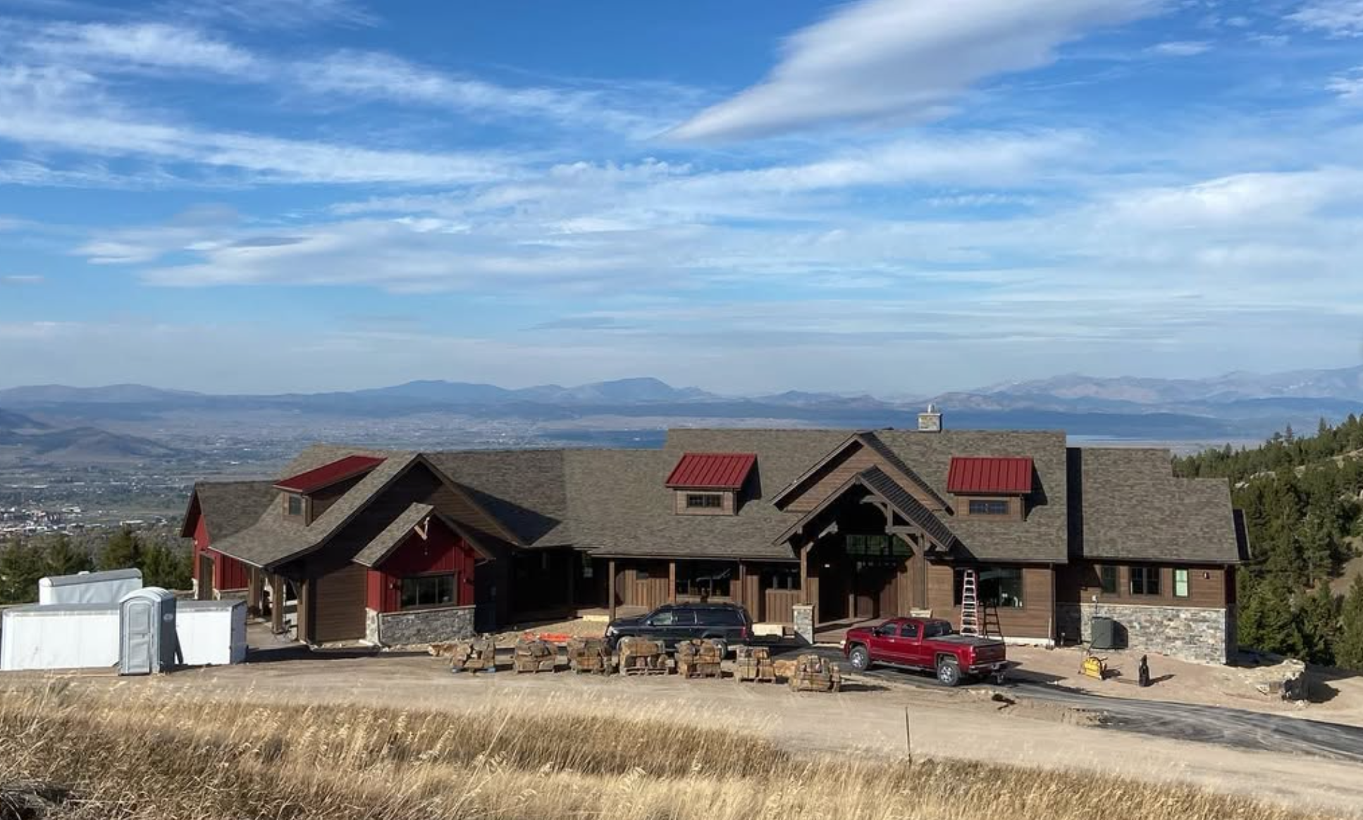 Custom timber frame home with deck and mountain backdrop in Montana