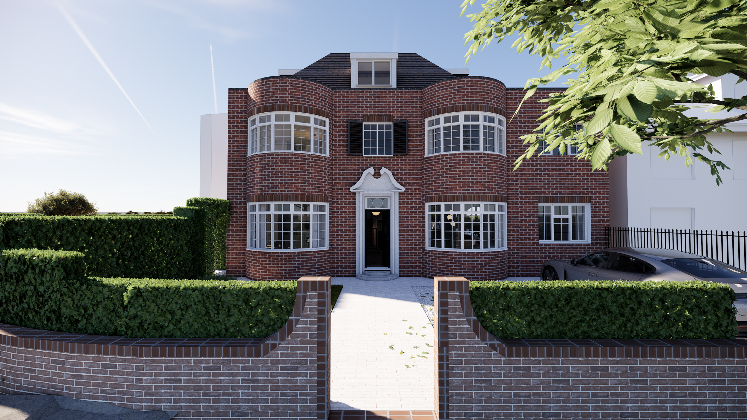 A red brick house with rounded bay windows, black shutters, and a decorative white arch over the entrance, surrounded by a brick wall and trimmed hedges, with a parked car on the right and trees in the foreground.