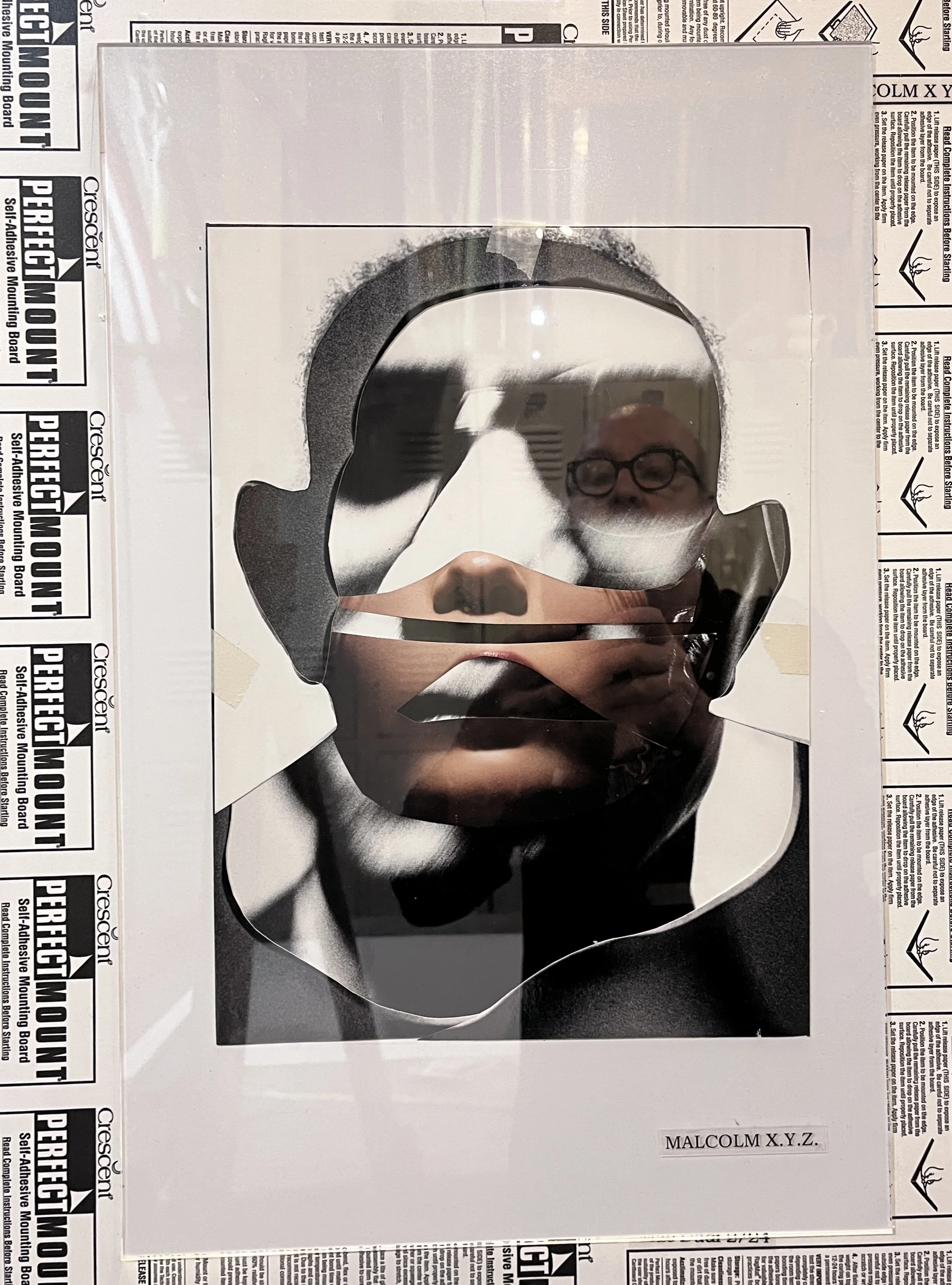 A poster with a cut-out mirror featuring a male face wearing glasses, with newspaper clippings surrounding it. The poster has the name 'Malcolm X.Y.Z.' at the bottom.