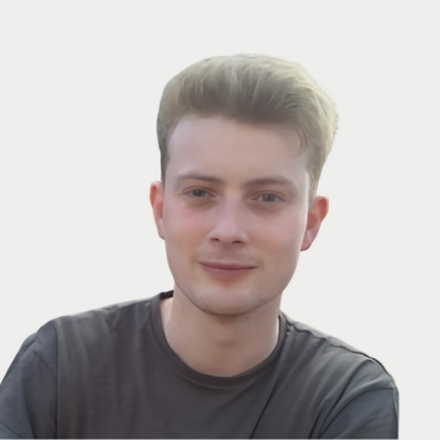 Portrait of a young man with short blond hair, smiling, wearing a dark t-shirt, against a plain white background.