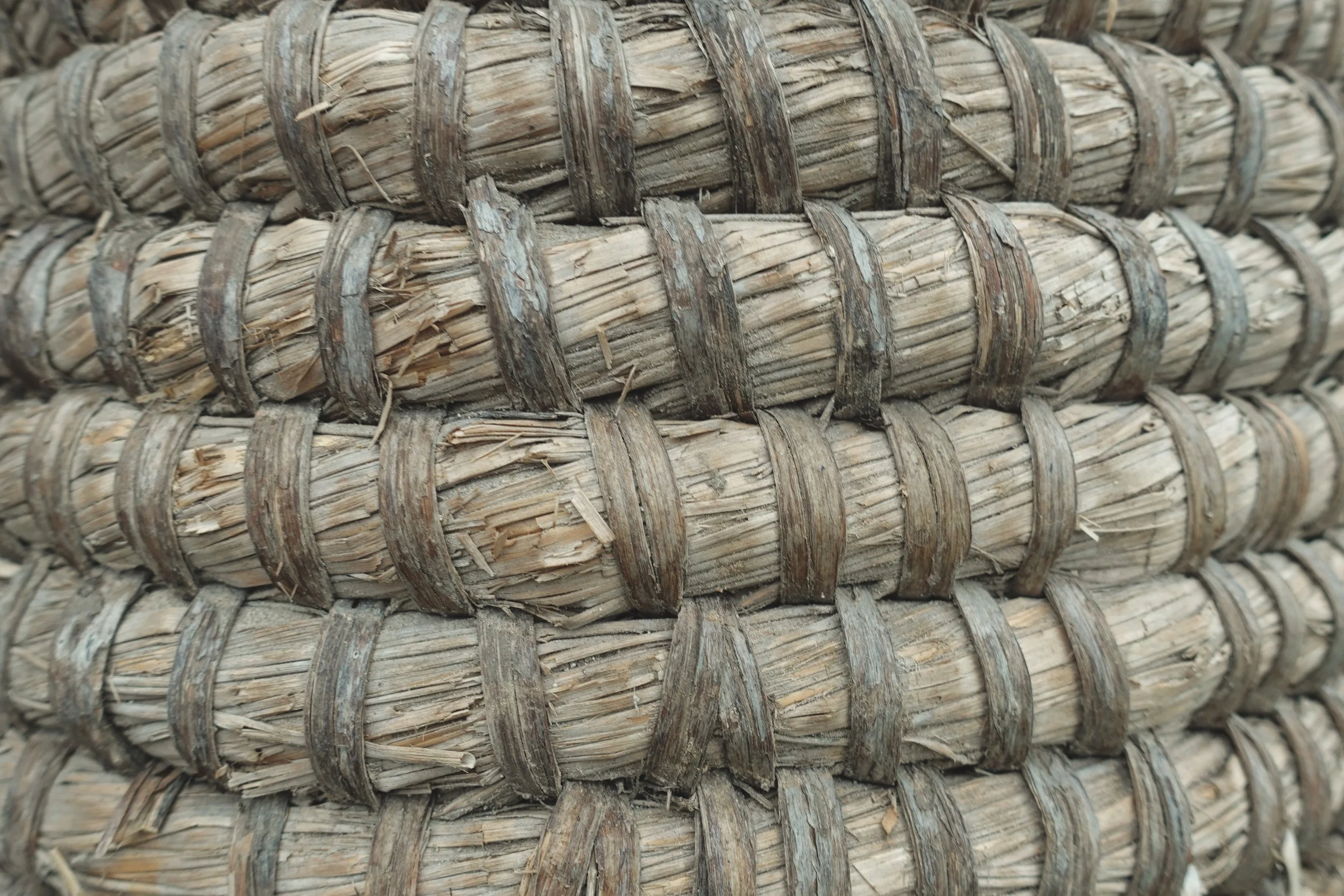 Close-up view of stacked straw or dried plant material wrapped with thin, dark bands