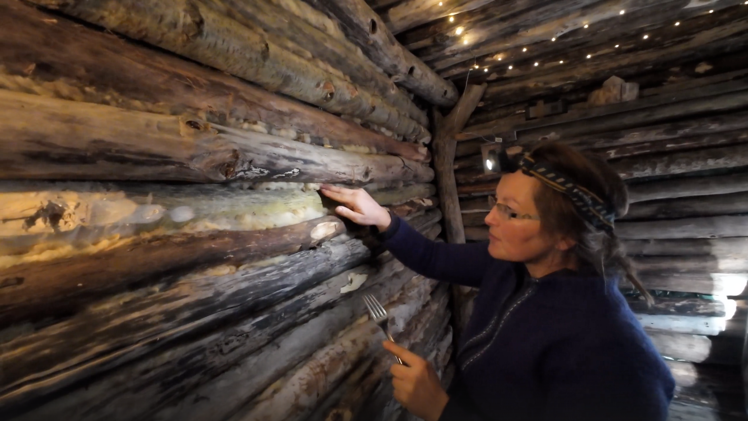 Een vrouw die in een hut met houten muren nachthoningbijen inspecteert.