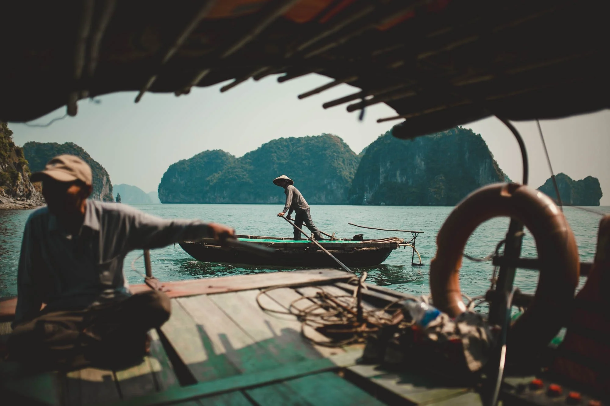 Fishermen on traditional boats in a seascape with limestone islands in the background.