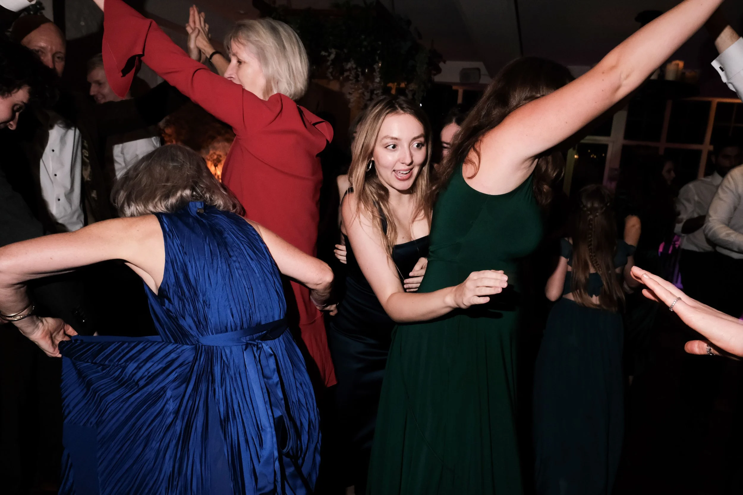 People dancing at a party or celebration, with women in colorful dresses enjoying themselves.