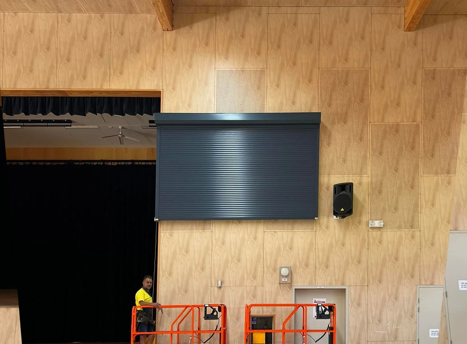Indoor stage with black curtains, large black rolling shutter.