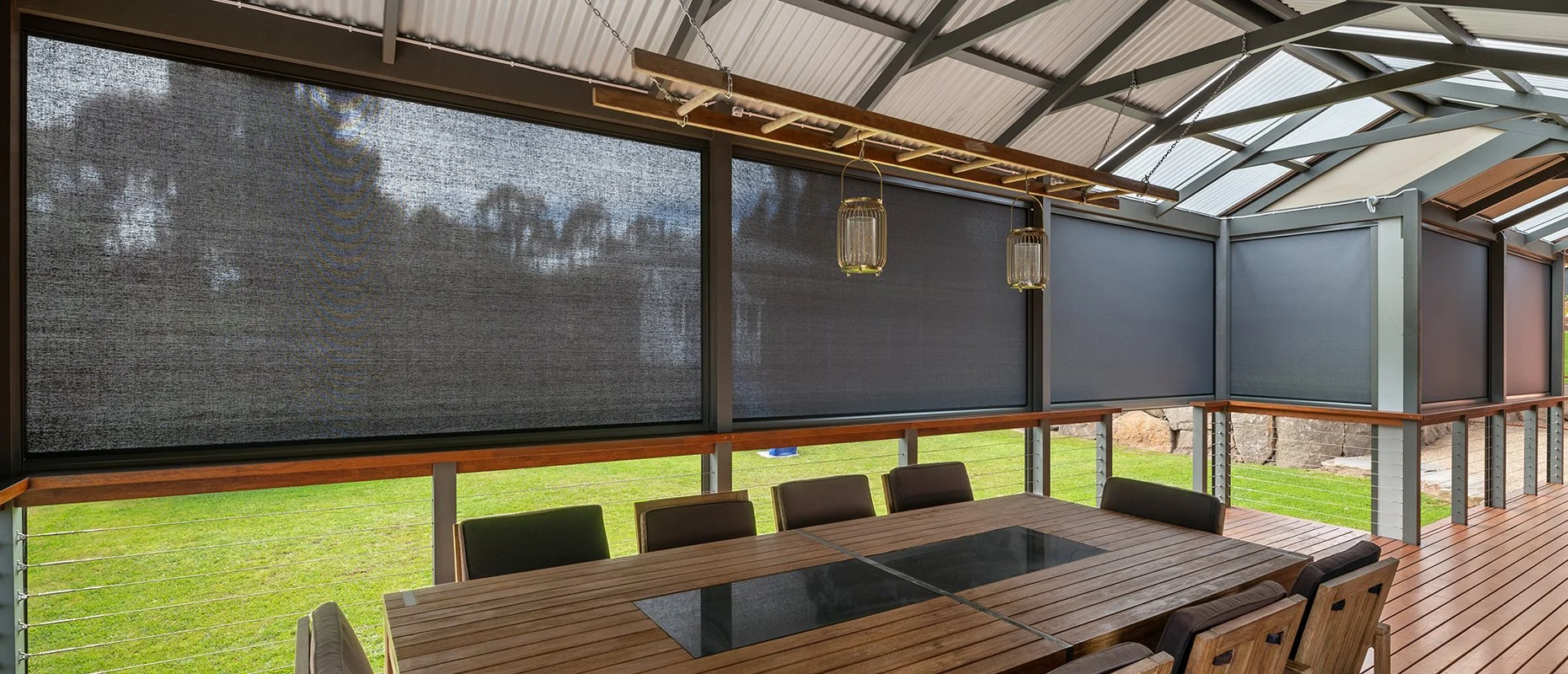 Outdoor covered patio with a wooden dining table surrounded by chairs, protected by eZip shutters in Sydney.