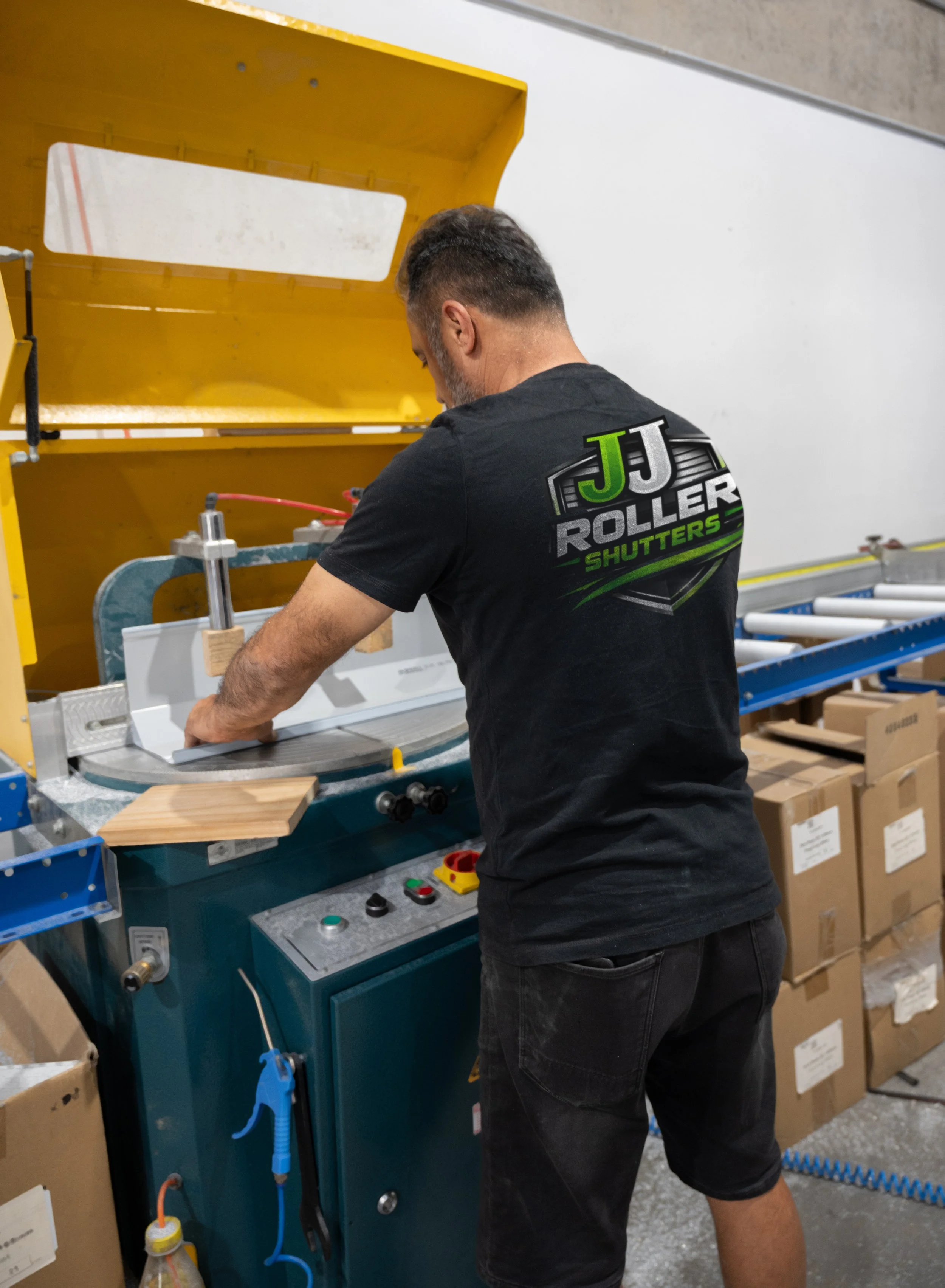 A man operating a machine in a workshop in Smeaton Grange Sydney, with boxes stacked on the floor nearby.