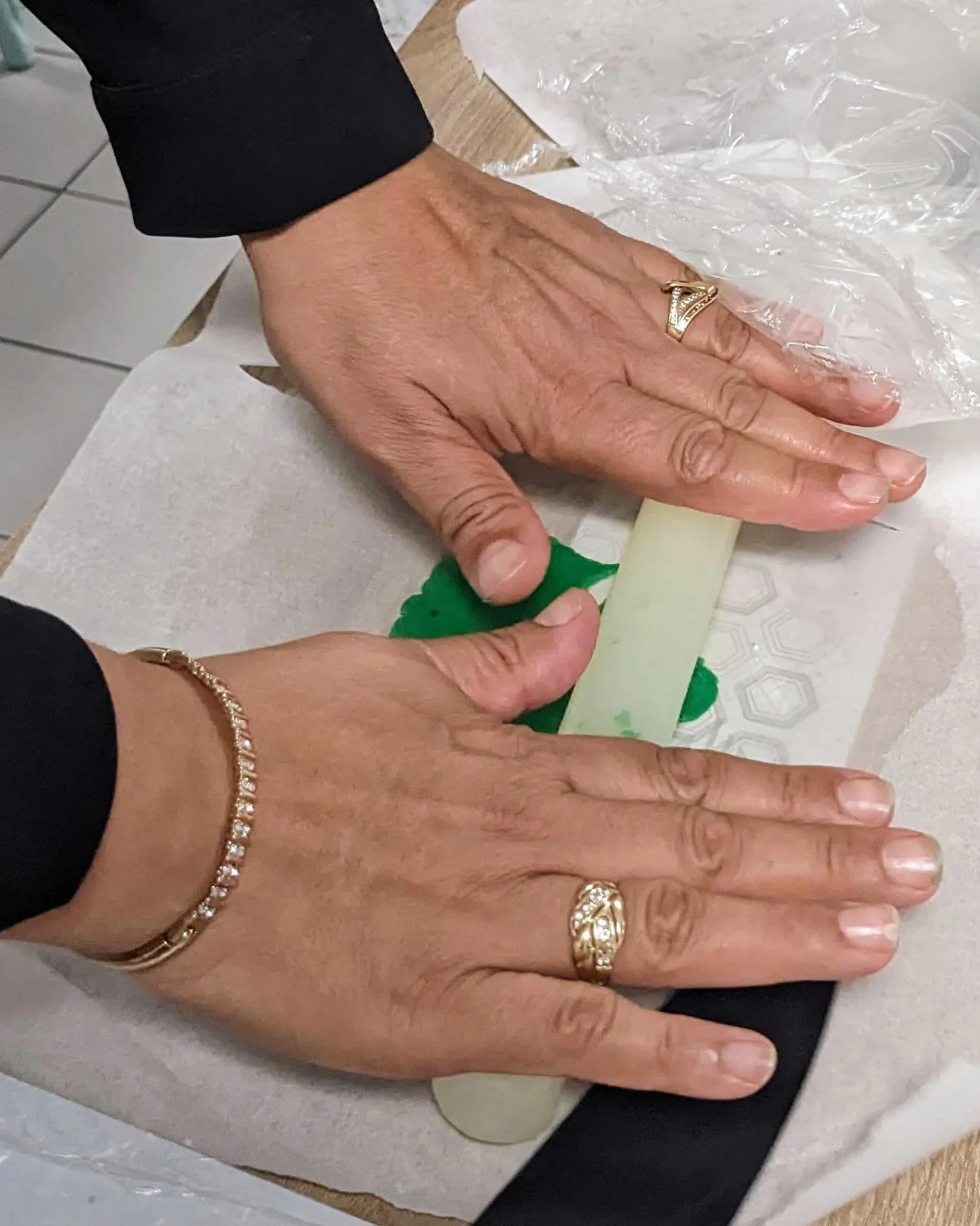 Mains d'une participante étalant une pâte à sablés vert vif, illustrant la pratique artistique en cuisine.