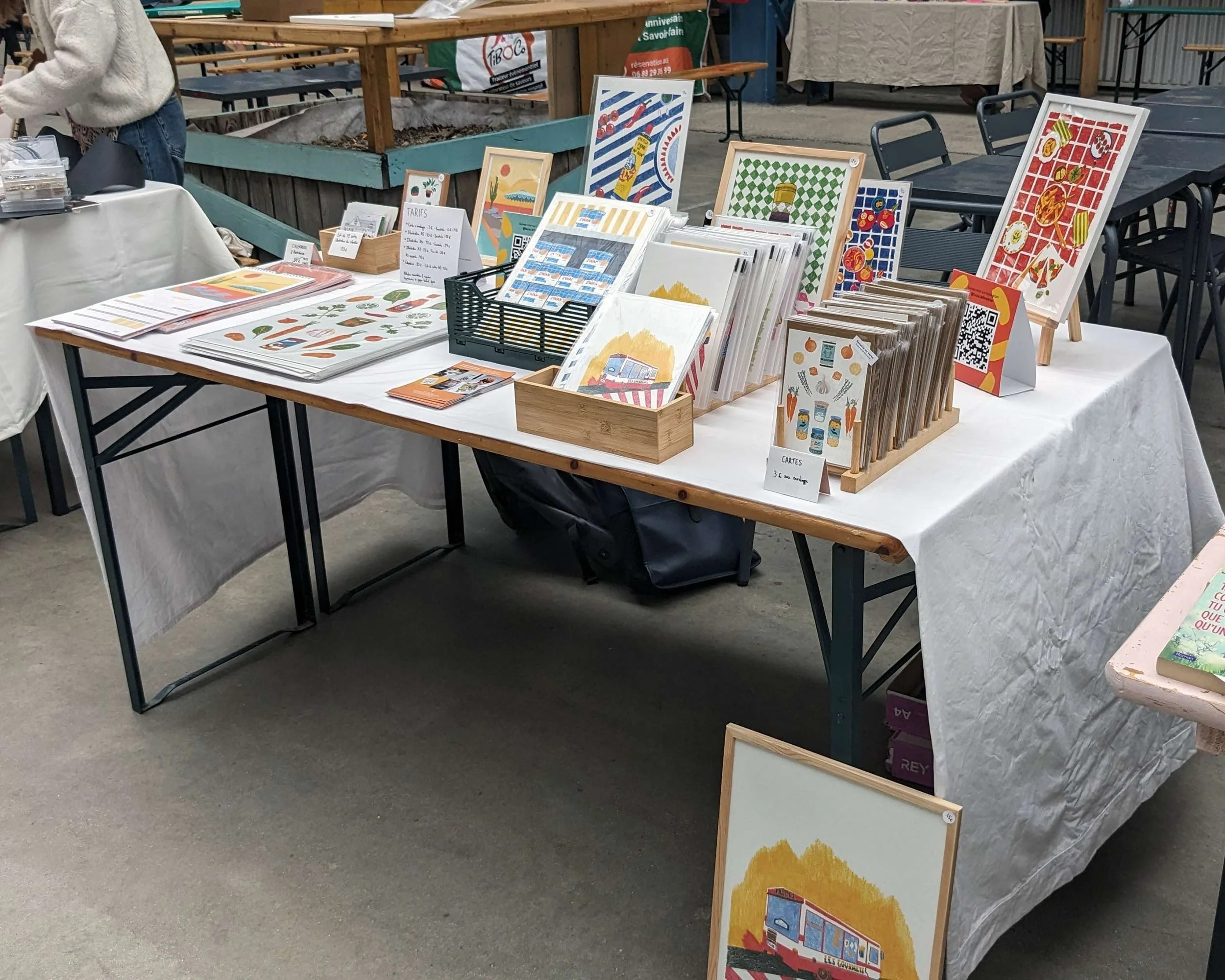 Lucie Leforestier présentant ses reproductions d'illustrations sur un marché de créateurs, tirages d'art en série limitée.