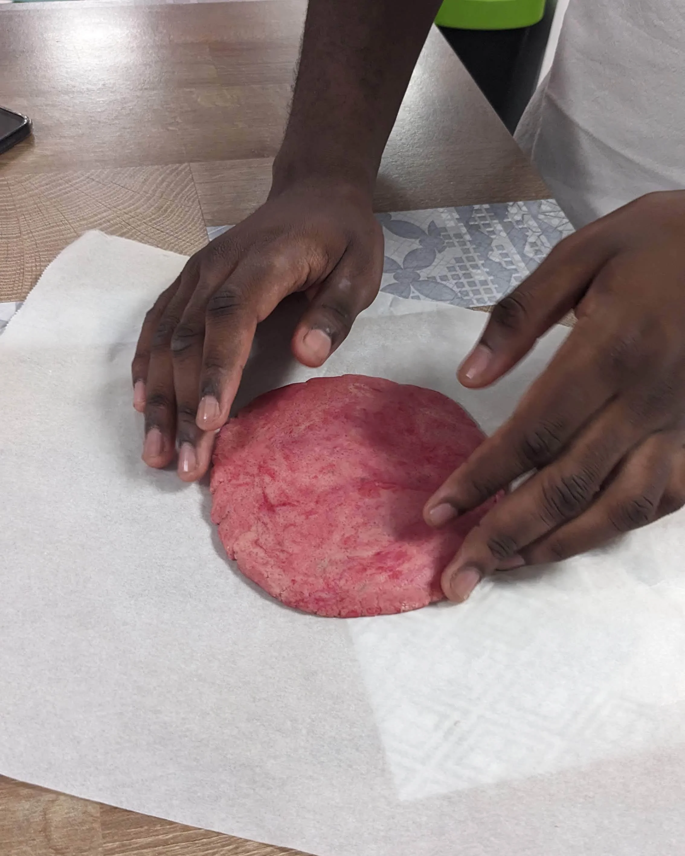 Adolescent modelant une pâte rose intense, jeu de contrastes et de couleurs pour l'œuvre comestible.