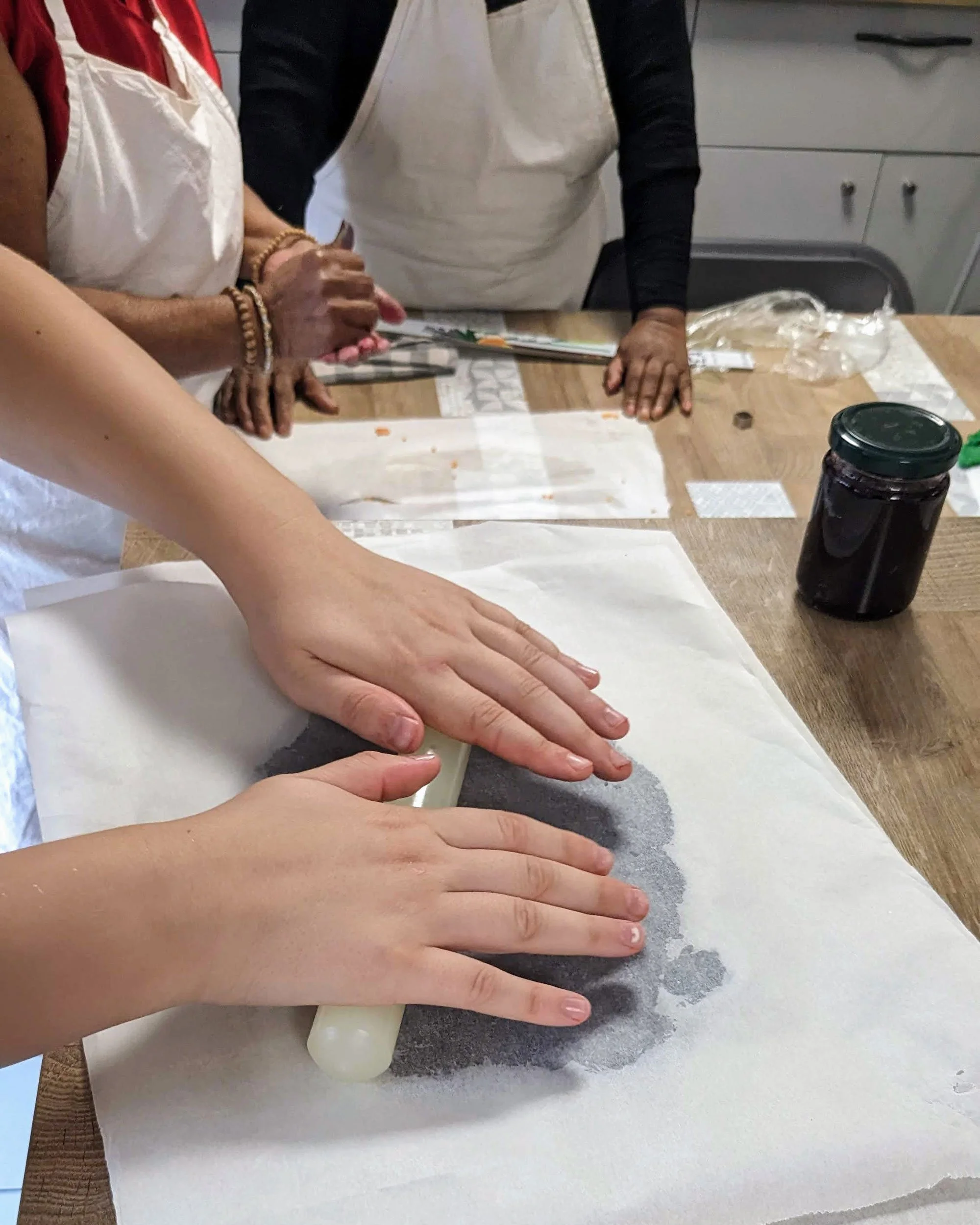 Étallage d'une pâte à biscuits noire entre deux feuilles de papier sulfurisé pour un rendu graphique.