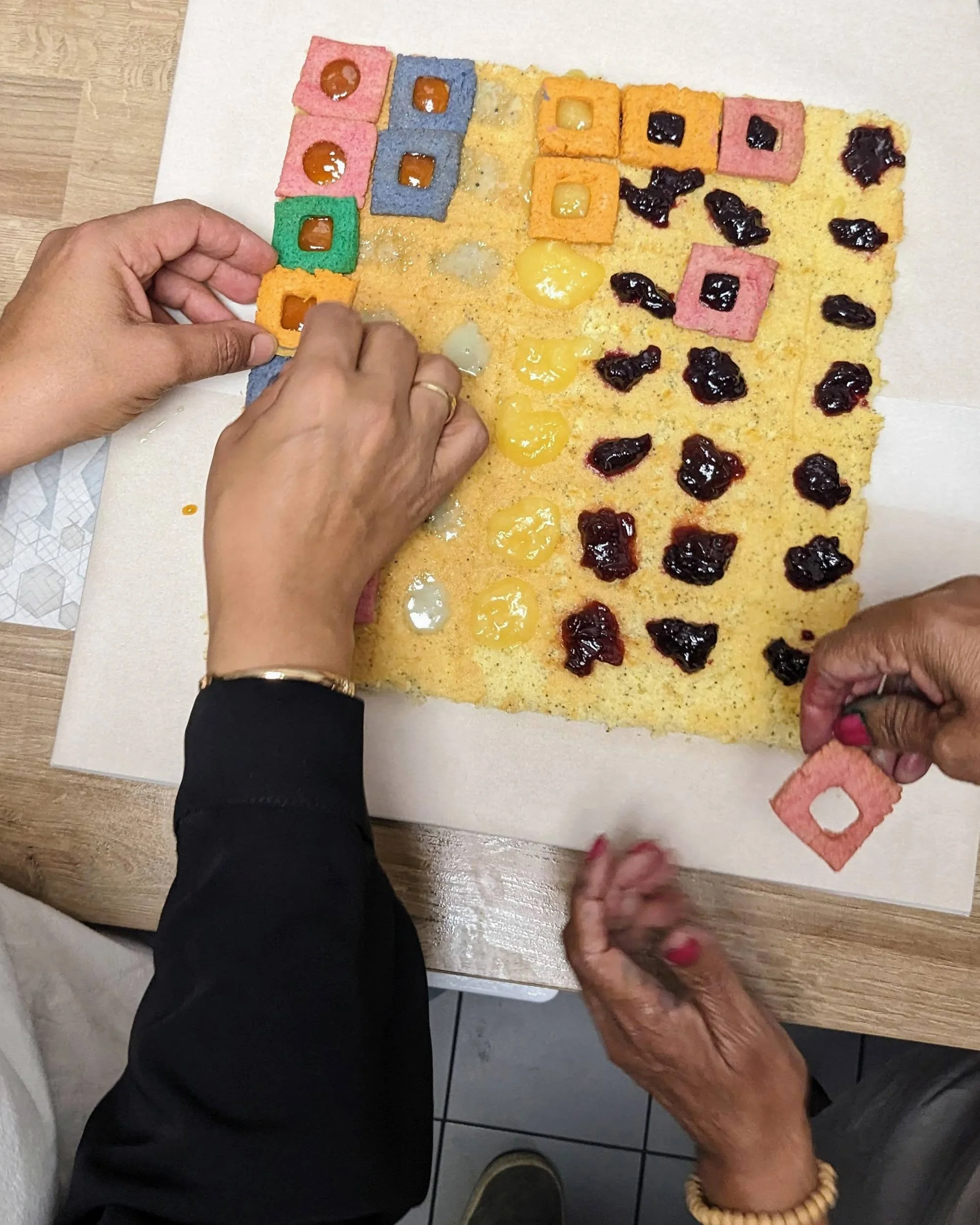 Plusieurs participants collaborant pour disposer les éléments géométriques sur la génoise au pavot.